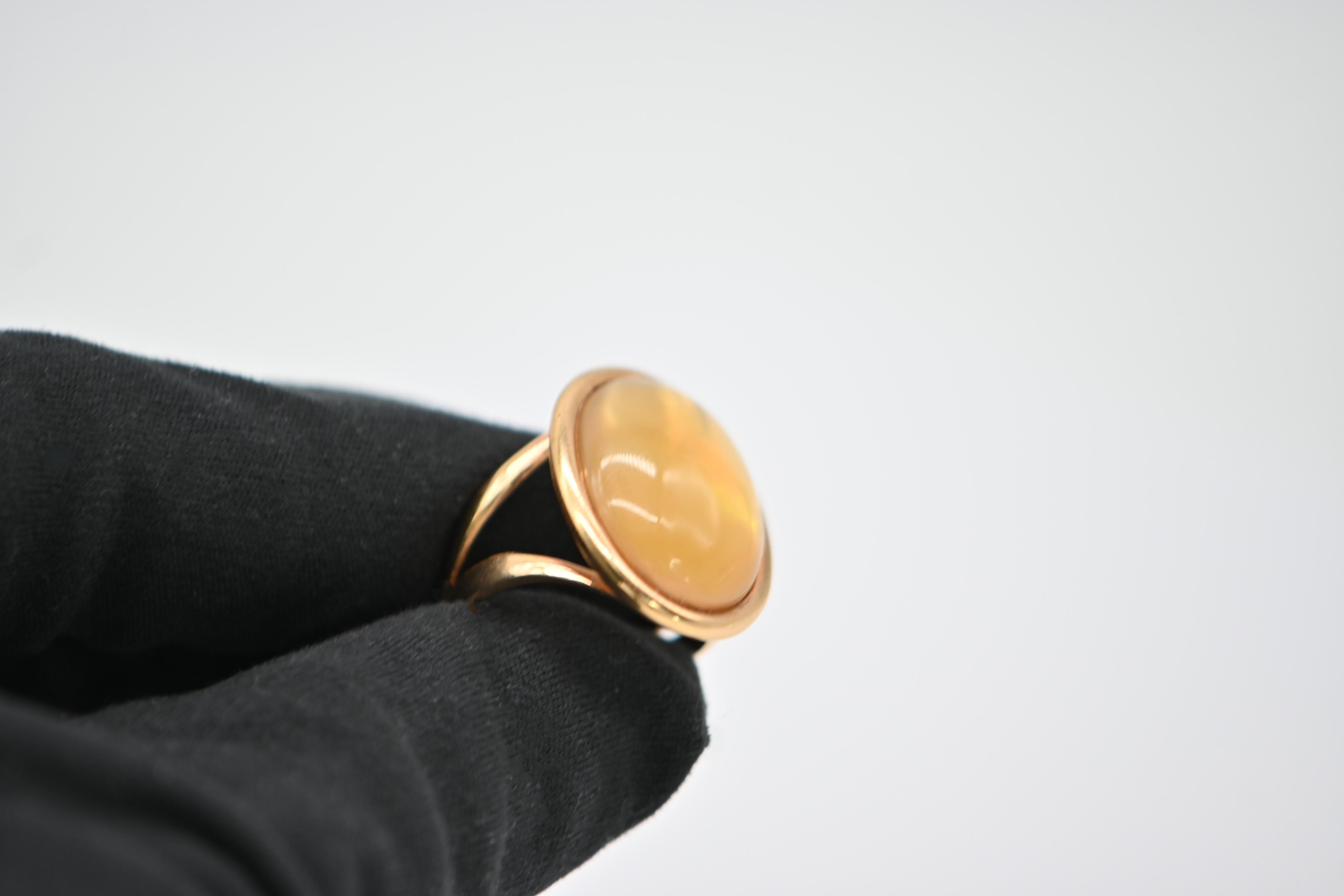 Une bague raffinée et originale qui joue avec la lumière et la transparence. Au premier coup d'œil, on aperçoit un cabochon de citrine lumineux serti sur un bracelet en or jaune 18K poli. Mais en y regardant de plus près, on découvre un détail