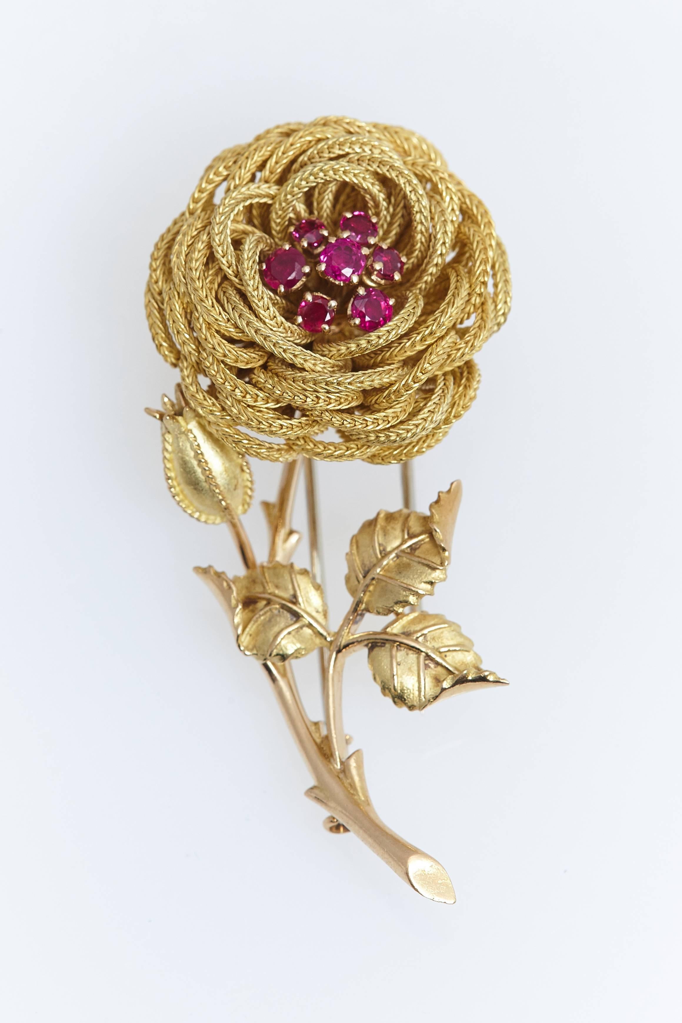 Pair of eighteen karat yellow gold and ruby flower design ear clips and matching brooch. The ear clips measure 3/4 inch in diameter. The brooch is 2 1/4 inch in length.  The pieces are signed "Made in France" and "18K."