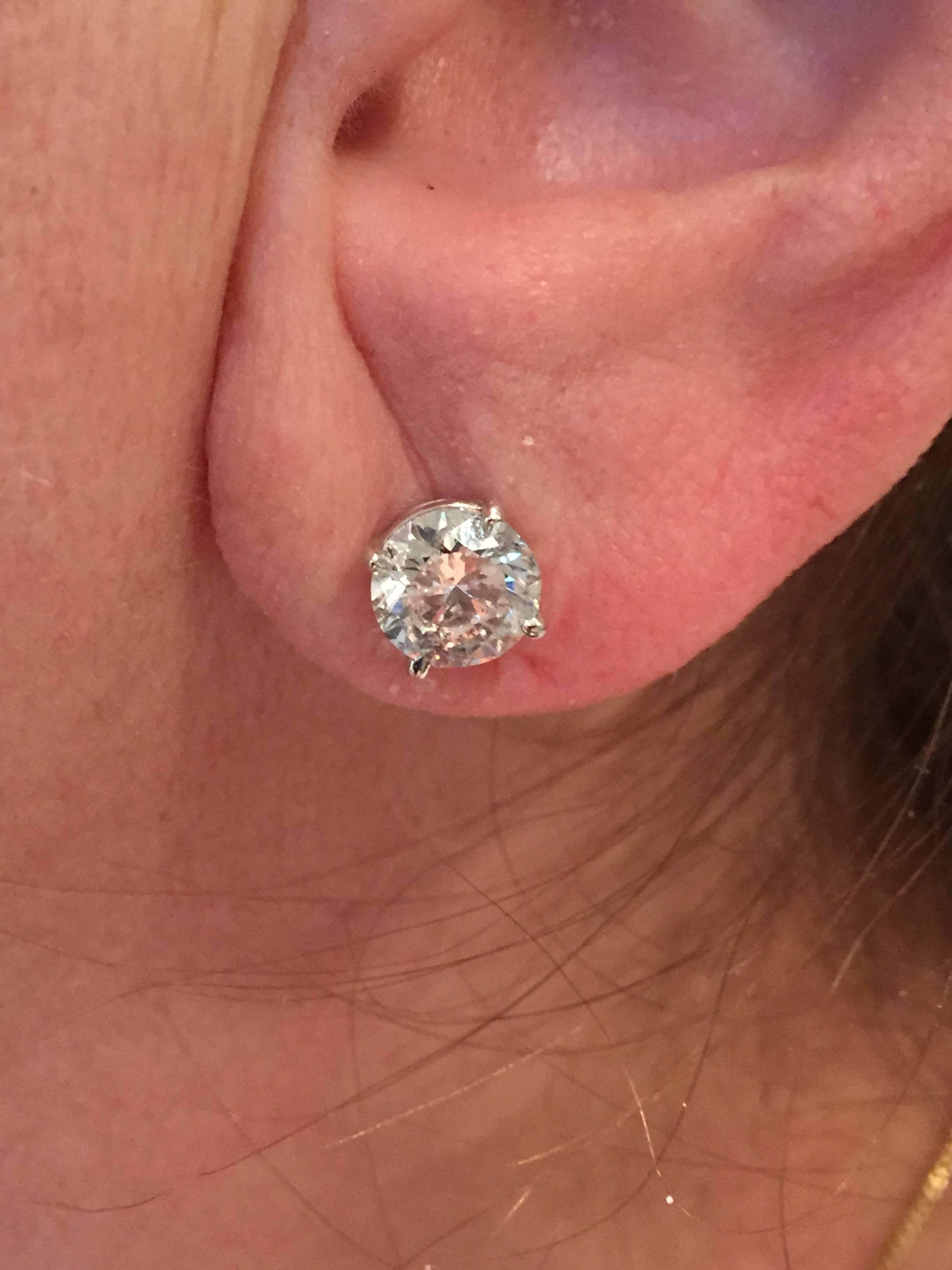 Two round diamonds weighing a total of weight of 3.41 carats mounted in classic four prong, white gold fourteen karat pushback earrings.  The two diamonds have a total weight of 3.41 carats.  The diamonds have grading reports from the European