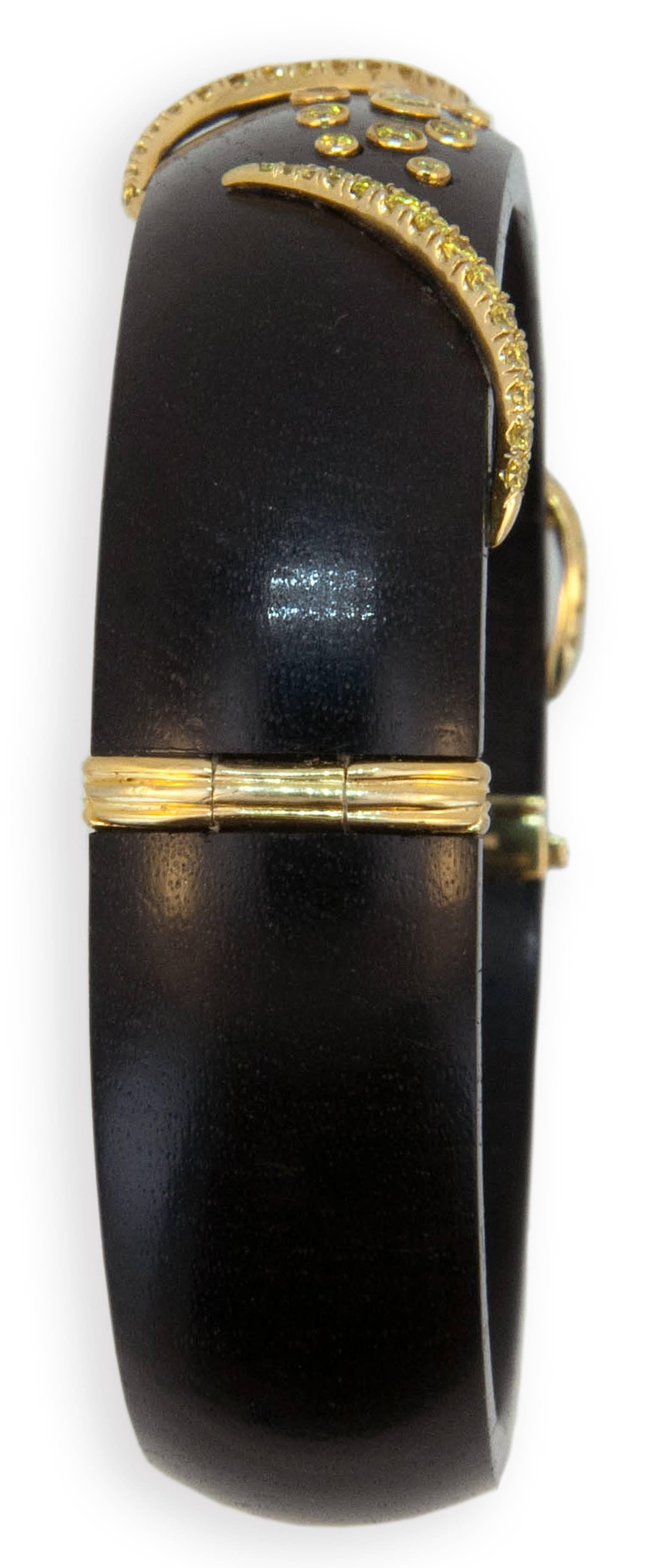 18 karat yellow gold on Grenadill wood bangle 5/8 inches wide three swirl designs are set with (52) round yellow diamonds and (10) various size yellow diamonds are tube set, total weight of (62) yellow diamonds is .97 carat total weight  