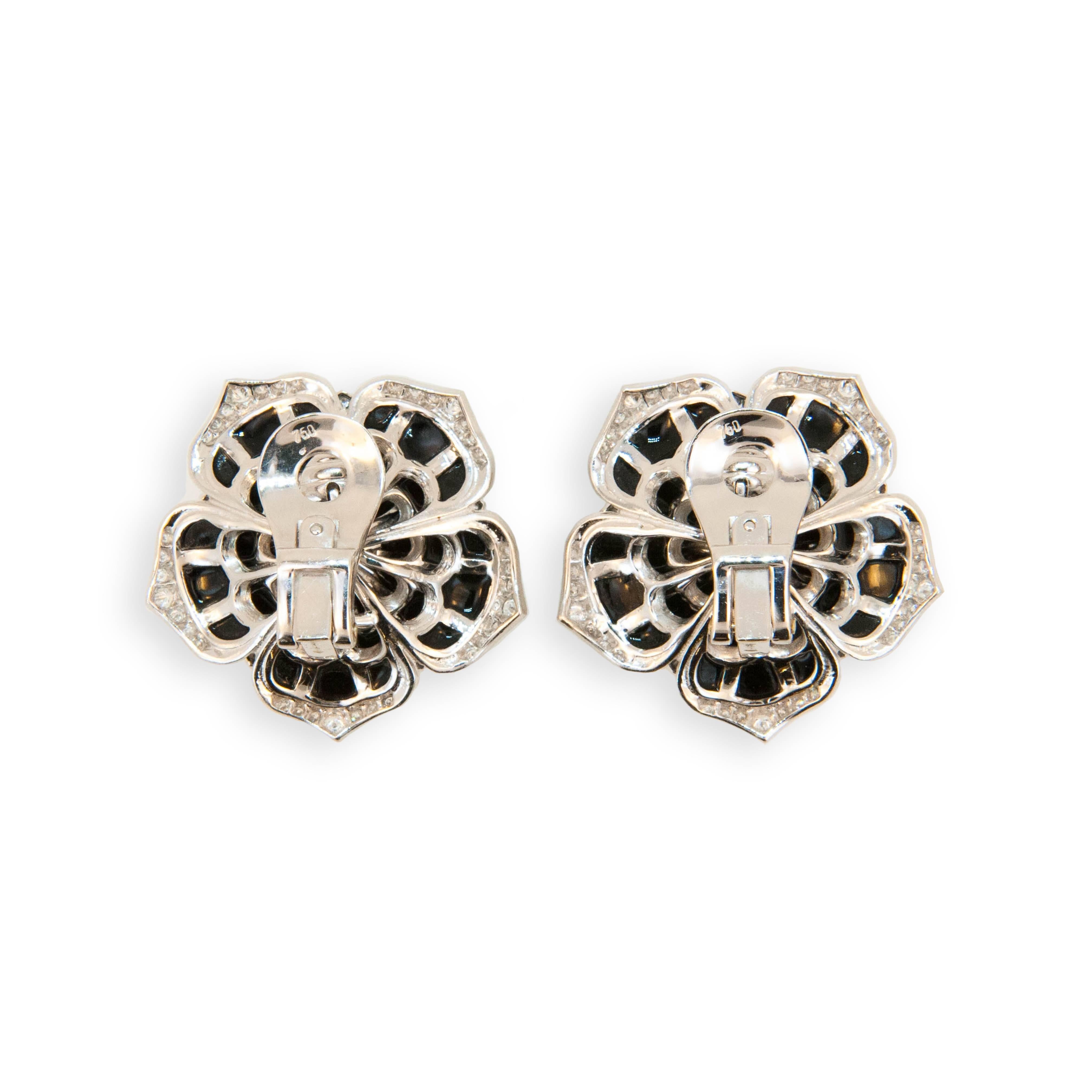 18 karat white gold flower style earrings set with 35 pieces of onyx in each earring 70 total. Edges of petals are set with 150 round diamonds 1.05 carats total weight and center of each flower is set with one rose cut diamond two equal .51 carats