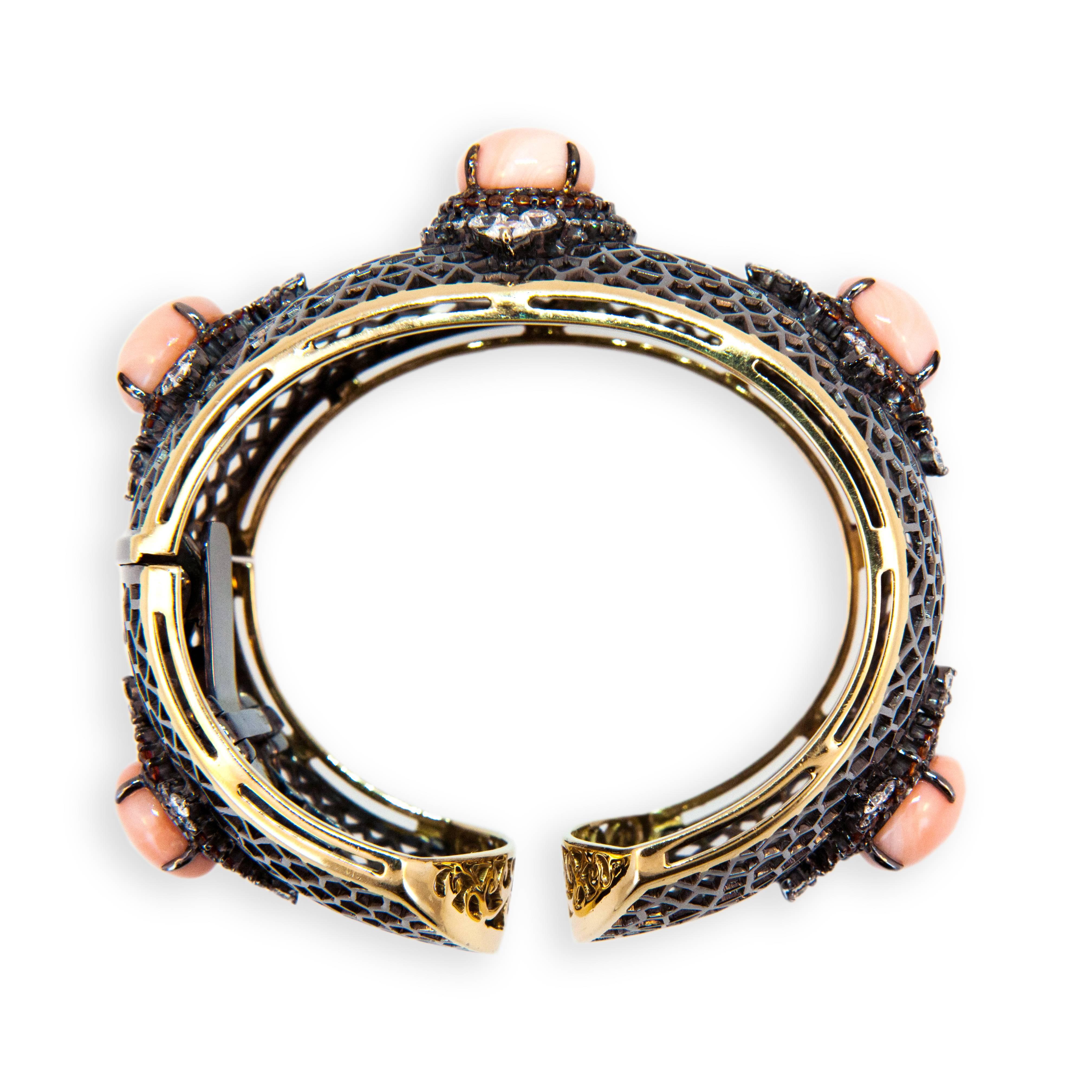 18 karat yellow gold blackened hinged cuff bracelet open web design with five 12.2-12.5 mm Angel Skin Coral Cabs 40.24 carats total weight. 110 Orange Sapphires 3.67 carats total weight. 83 full-cut diamonds 4.51 carats total weight.
