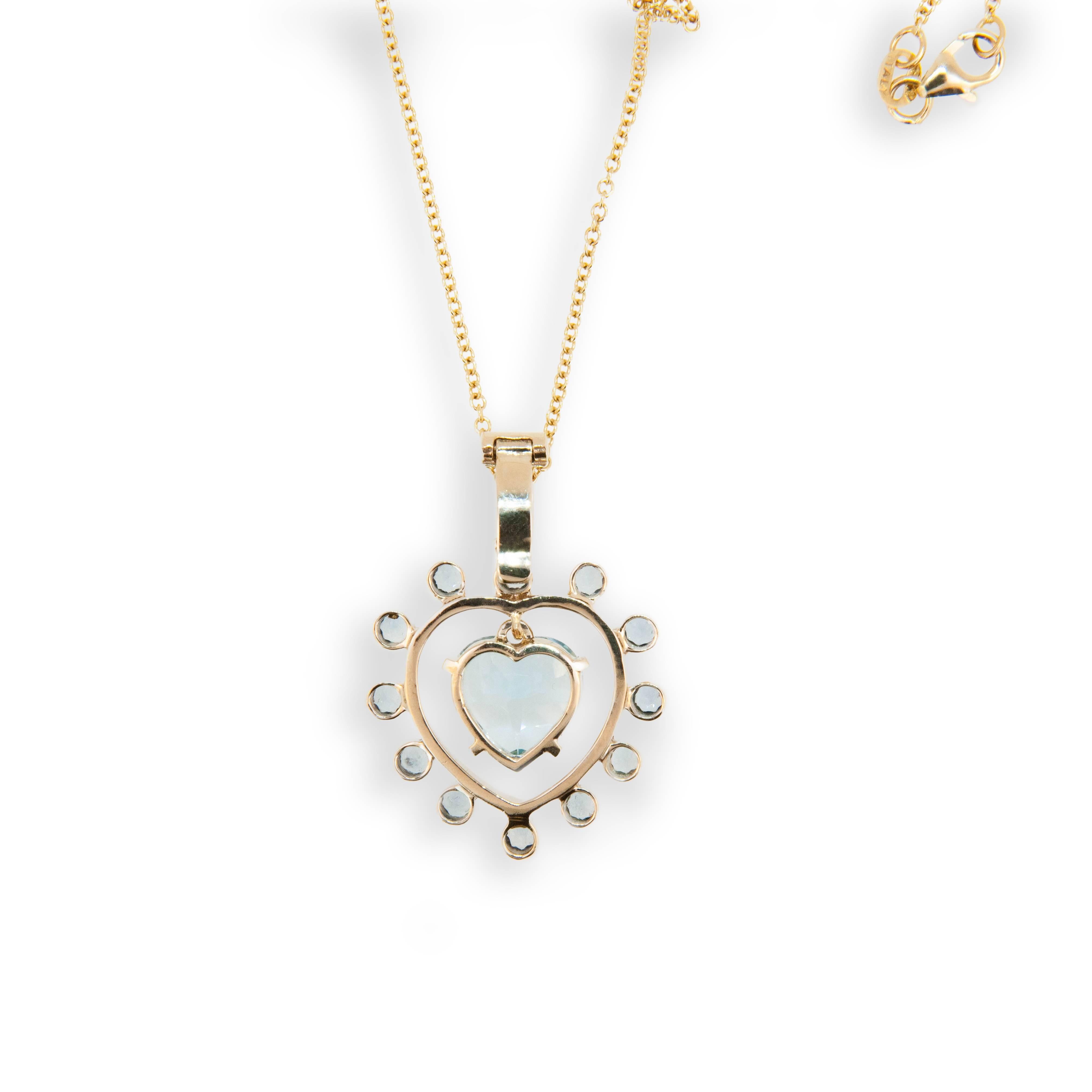 14 karat yellow gold Sweetheart pendant; heart shaped Blue Topaz 5.94 carats surrounded by twelve 2.8 mm round faceted blue topaz  .99 carats total weight round blue topaz. Heart shaped blue topaz swings freely in center. Pendant bail opens and