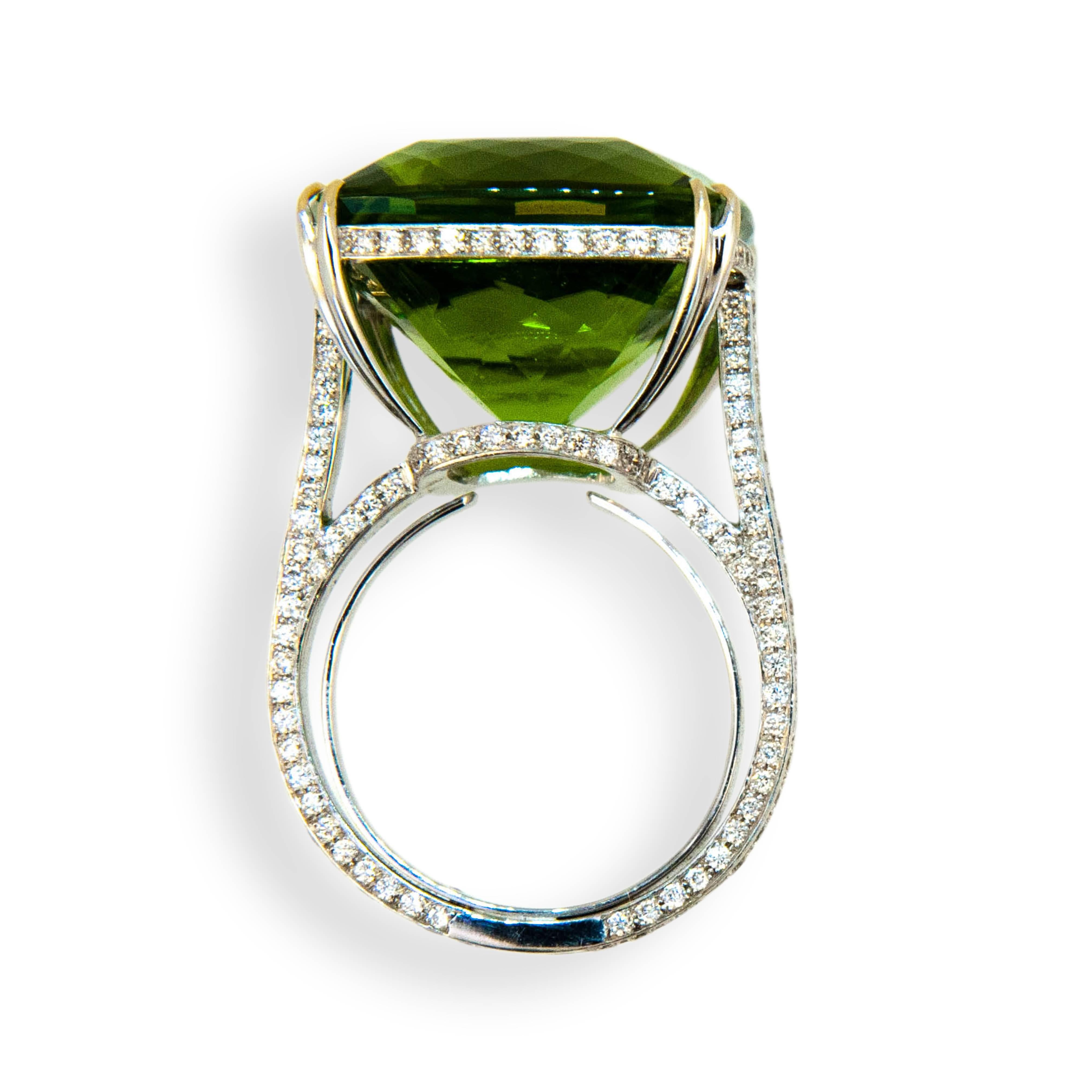 18 karat white gold ring , set in center is one 26.78 carats square faceted cushion cut Peridot. Mounting is set with 226 round diamonds .9-1.4 mm, 1.05 carats total weight. Diamonds are set on under bezel and all sides of shank. Tapered split