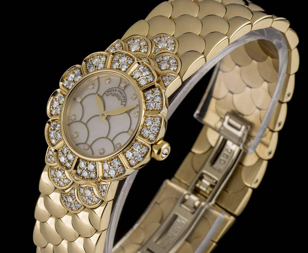 An 18k Yellow Gold Cocktail Ladies Wristwatch, mother of pearl dial with a petal pattern motifs and 12 applied round brilliant cut diamond hour markers, a fixed 18k yellow gold bezel set with approximately 60 round brilliant cut diamonds, crown set