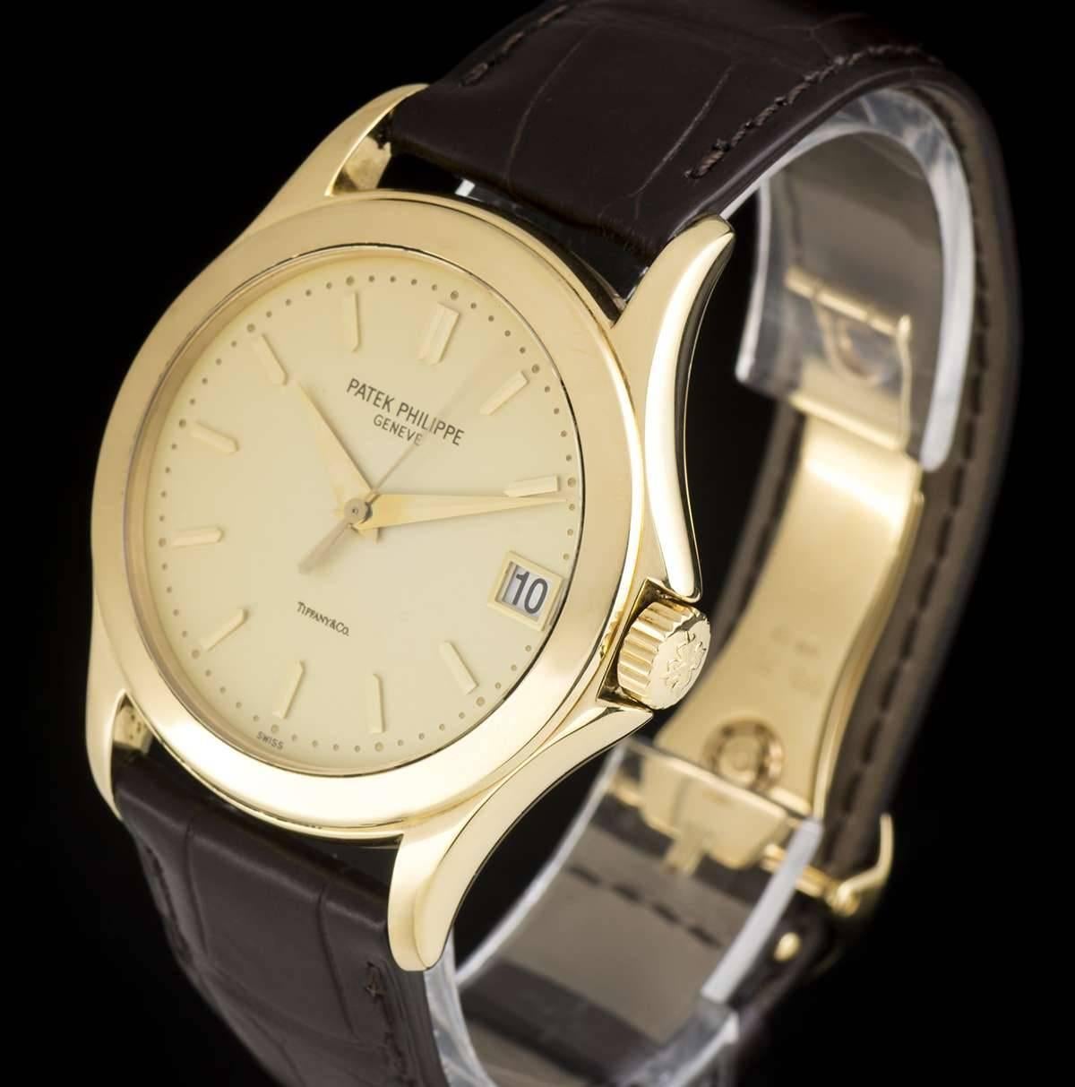 An 18k Yellow Gold Double Name Calatrava Gents Wristwatch, opaline silver dial (retailed by Tiffany & Co) with applied index batons, date at 3 0'clock, a fixed 18k yellow gold bezel, a brand new original brown leather strap with an original 18k