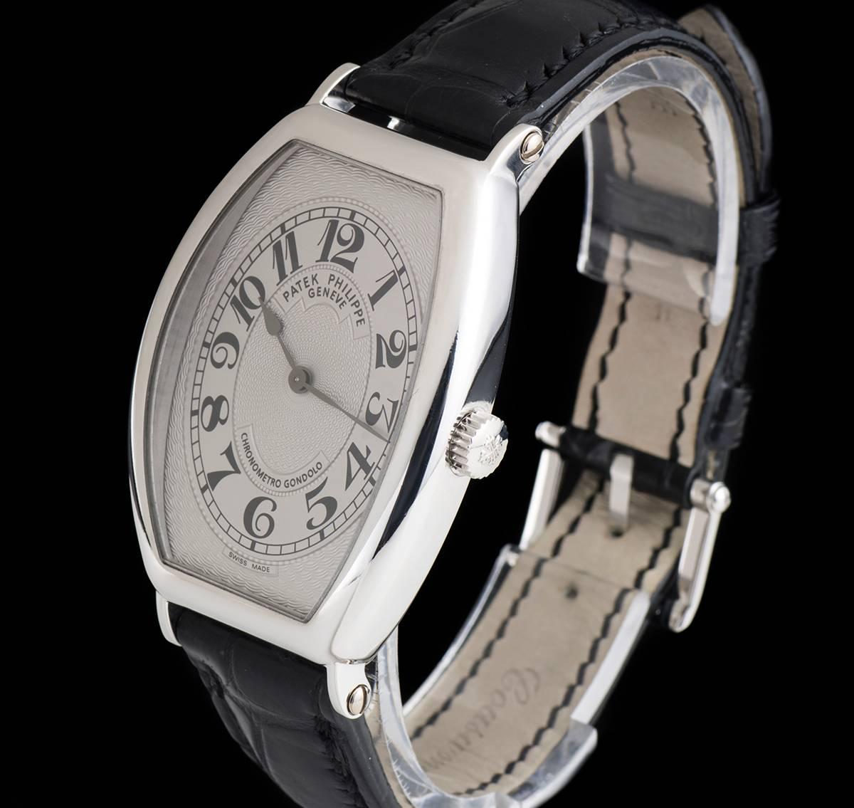 A Platinum Tonneau Shaped Gondolo Gents Wristwatch, silver guilloche dial with arabic numbers, a fixed platinum bezel, a original black leather strap with an original platinum pin buckle, sapphire glass, exhibition caseback, manual wind movement, in