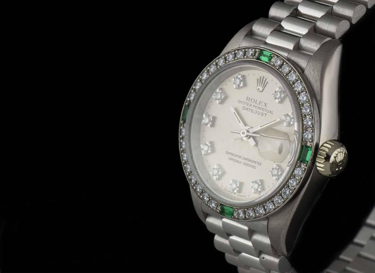 An 18k White Gold Oyster Perpetual Datejust Ladies Wristwatch, silver dial with 10 applied round brilliant diamond hour markers, date at 3 0'clock, a fixed 18k white gold bezel set with approximately 32 round brilliant cut diamonds and 4 emerald cut