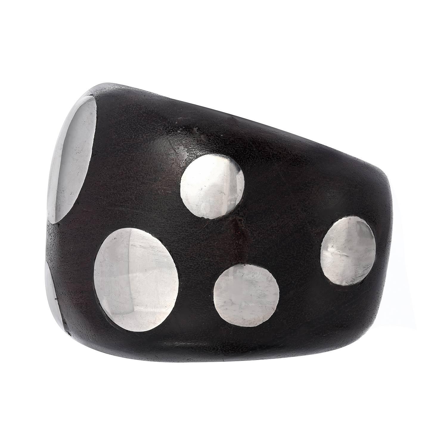 Designed as an ebony cuff, inlaid with silver discs