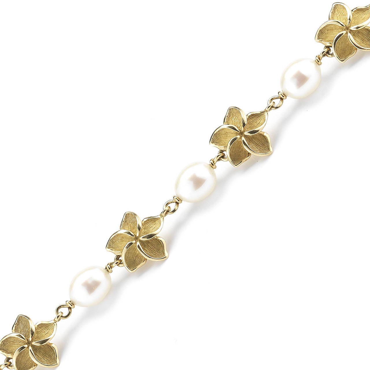 This Tiffany & Co. bracelet is classic and an elegant every day piece. The bracelet alternates between 18k gold flower  and pearls, adding a very feminine and floral touch to a gold bracelet. Stamped Tiffany & Co., 750.  It is 7