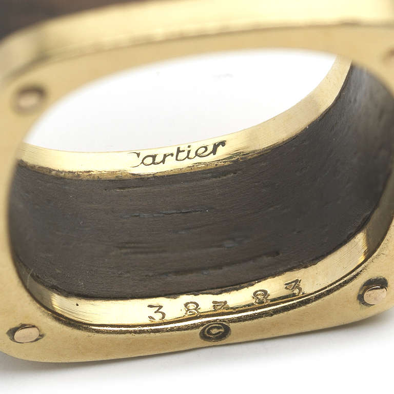 This gold and wood band ring is 18k and was designed in the 1970s. The piece has a wood body and clean lines. Signed Cartier. Size 5.25.