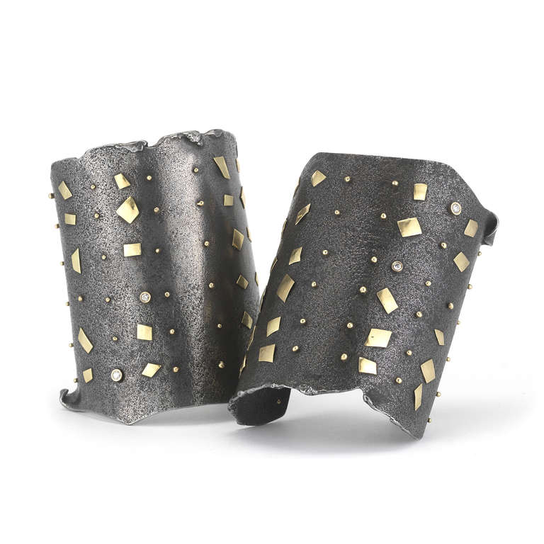 A contemporary pair of cuff bracelets which are handmade by Jaclyn Davidson are made of steel and 18K gold with four bezel set diamonds. The use of steel lends a quiet and down-to-earth presence to these bracelets. The 18K gold multi-shape elements