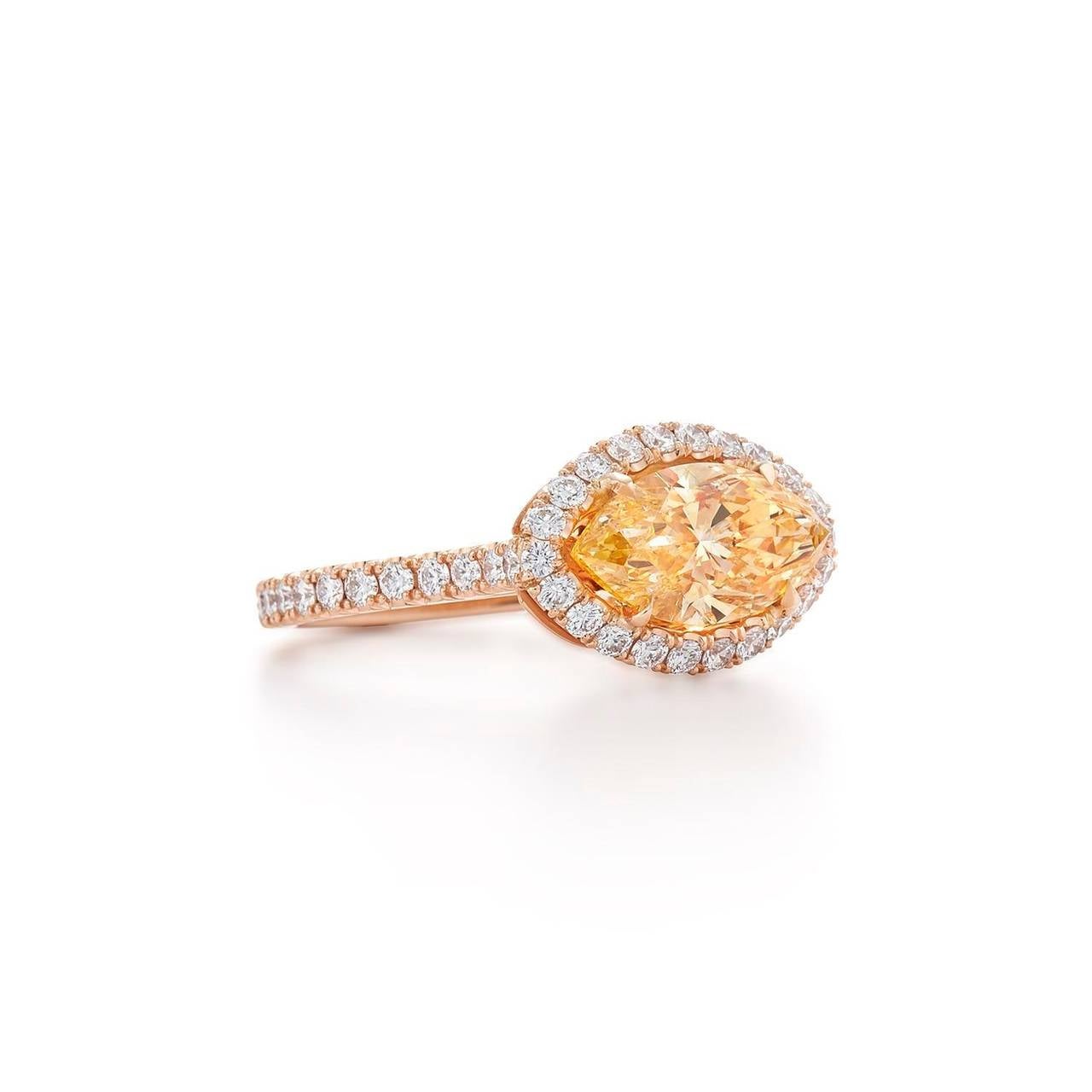 A spectacular marquise-cut fancy yellow orange diamond within a circular-cut diamond halo and set in 18K pink gold. The center diamond weighs weighing approximately 2.03 carats and the surrounding white diamonds weigh approximately 0.81 carats