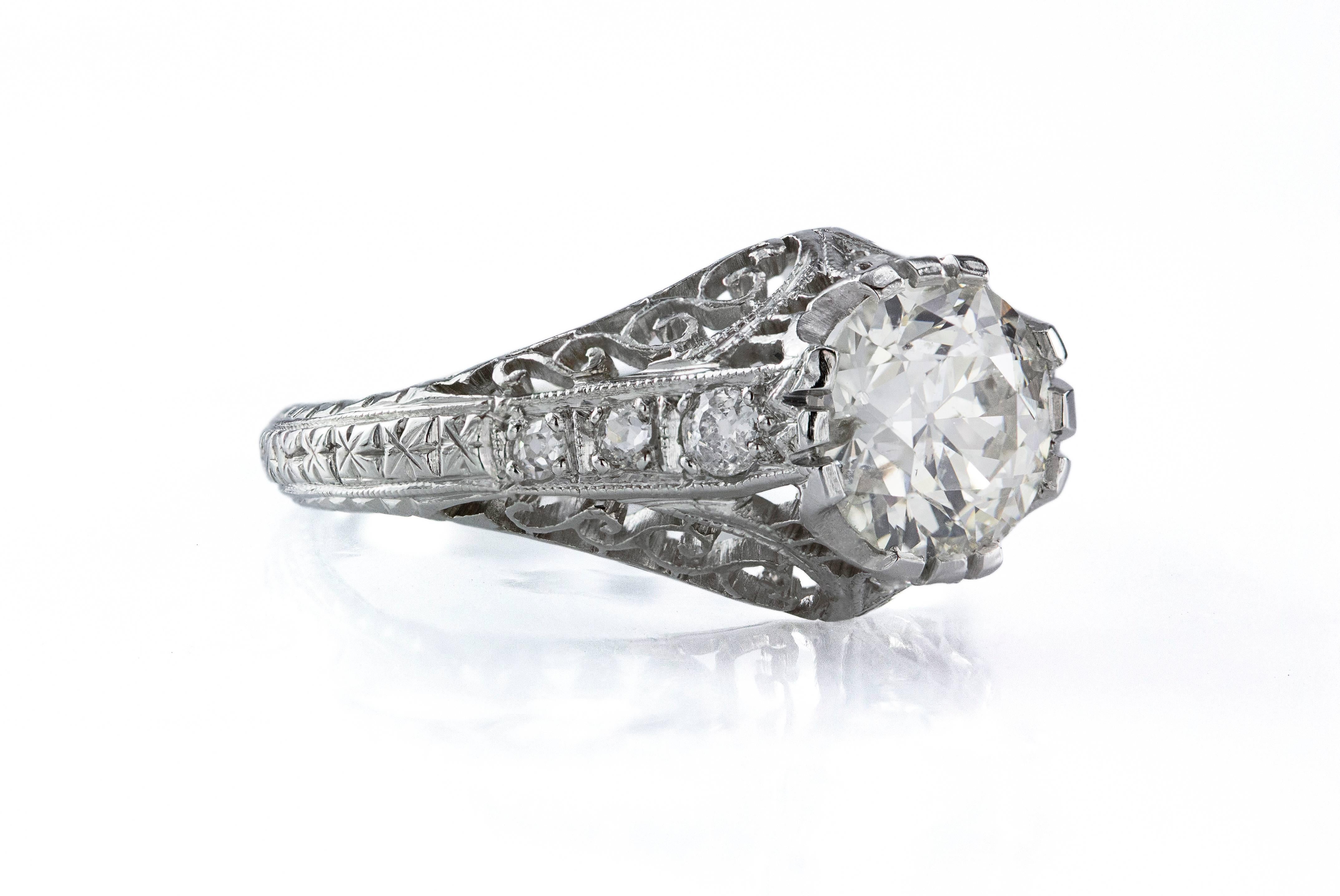 This antique ring features a brilliant round diamond center stone set in a beautiful intricate design. The center stone weighs 1.61 carats. The center stone is accented with 3 brilliant round diamonds on each side weighing 0.19 carats total. Size is