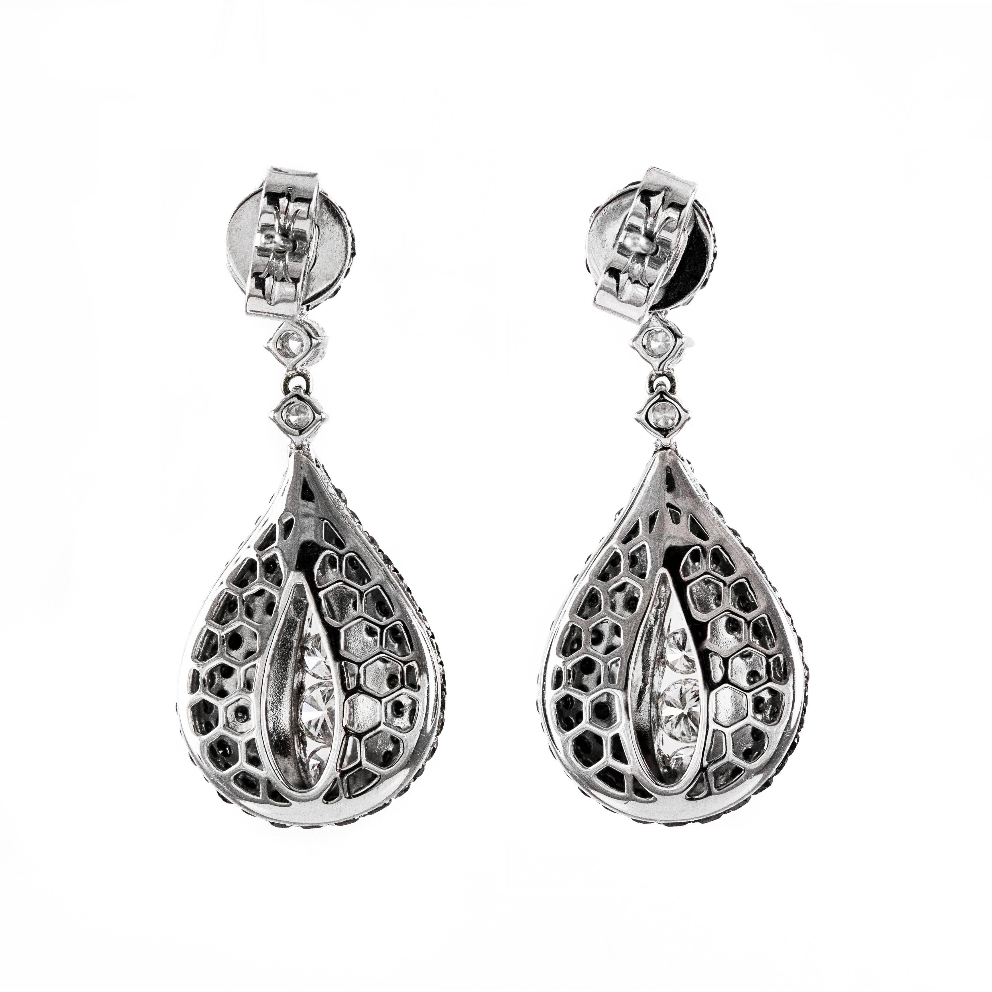 This pair of earrings features round brilliant white diamonds accented by round black diamonds pave set in round and pear shape. The total carat weight of the earrings is 3.18 carats. The top portion encompassing the bail has a micro pave setting of