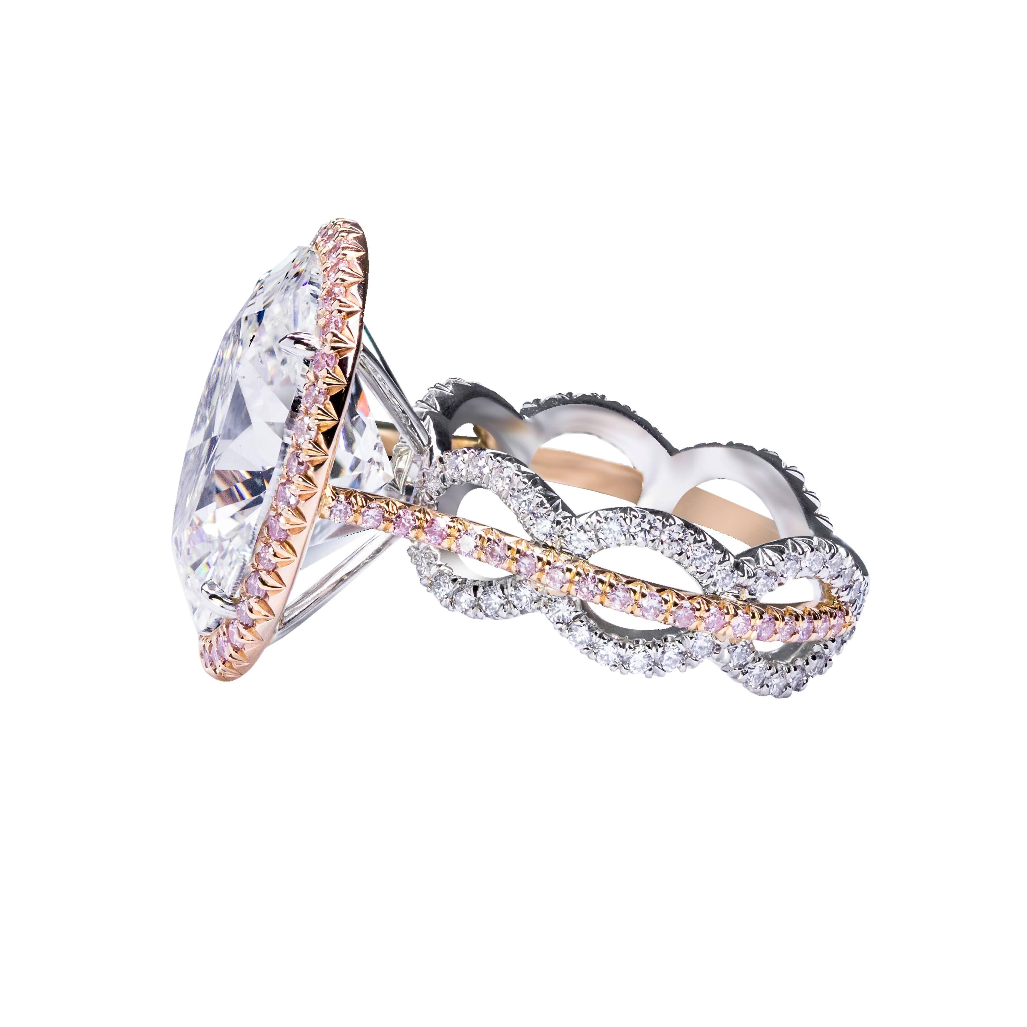 This ring features a 10.03 carat oval cut diamond center stone that HRD certified as D color and SI2 clarity. A single row of round brilliant pink melee diamonds surround the center stone. Set in a creative and intricate three row mounting set with