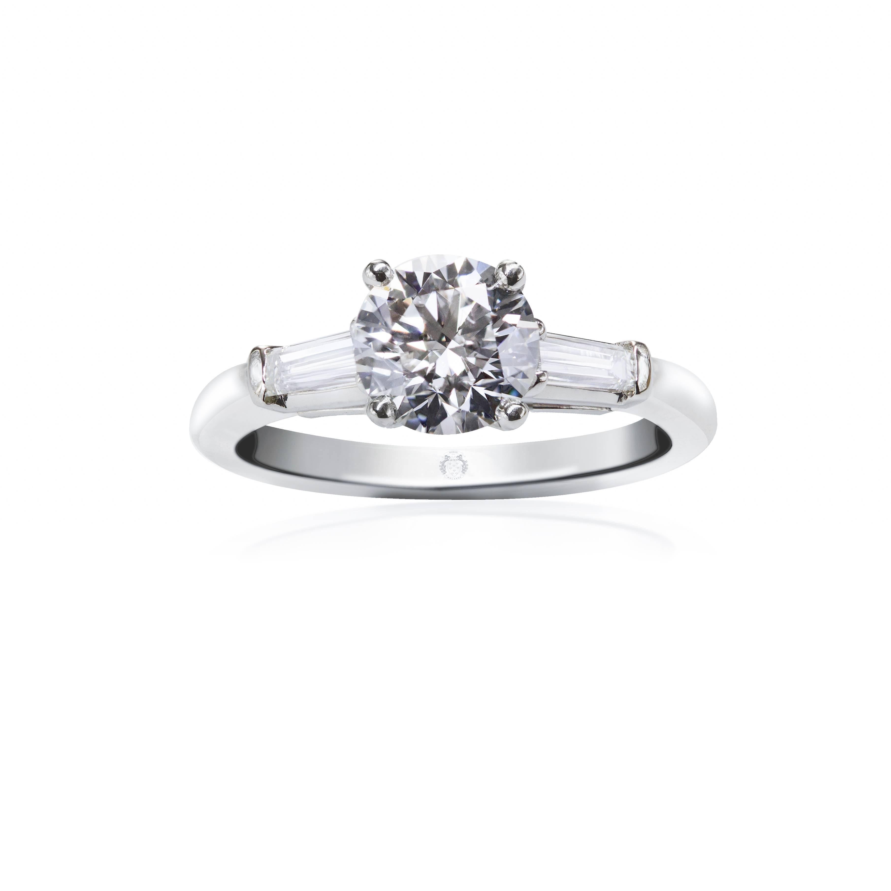 This engagement ring features a round brilliant diamond center stone that GIA certified as G color, VVS2 clarity. Tapered baguettes weighing 0.25 carats total accent the round center stone on either side. Set in platinum. Approxmate size 6 US