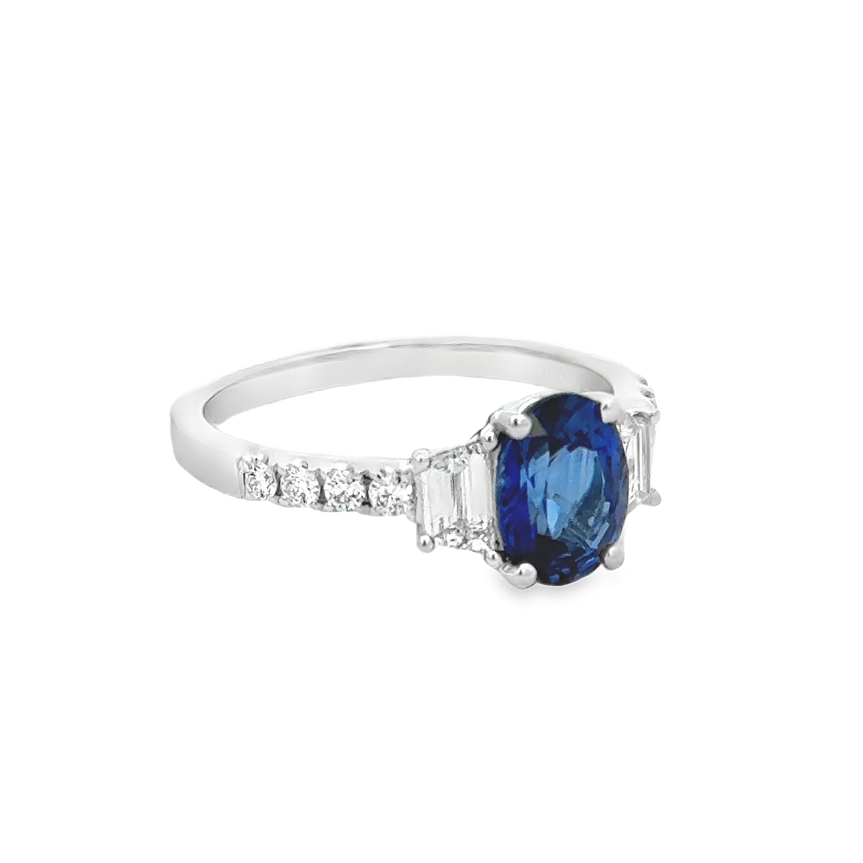 Une élégante bague de fiançailles, ornée d'un saphir ovale de 1,52 carats, serti sur une monture classique à quatre griffes. Flanquée de deux diamants de taille trapézoïdale pesant 0,39 carat au total et accentuée par des diamants ronds de taille