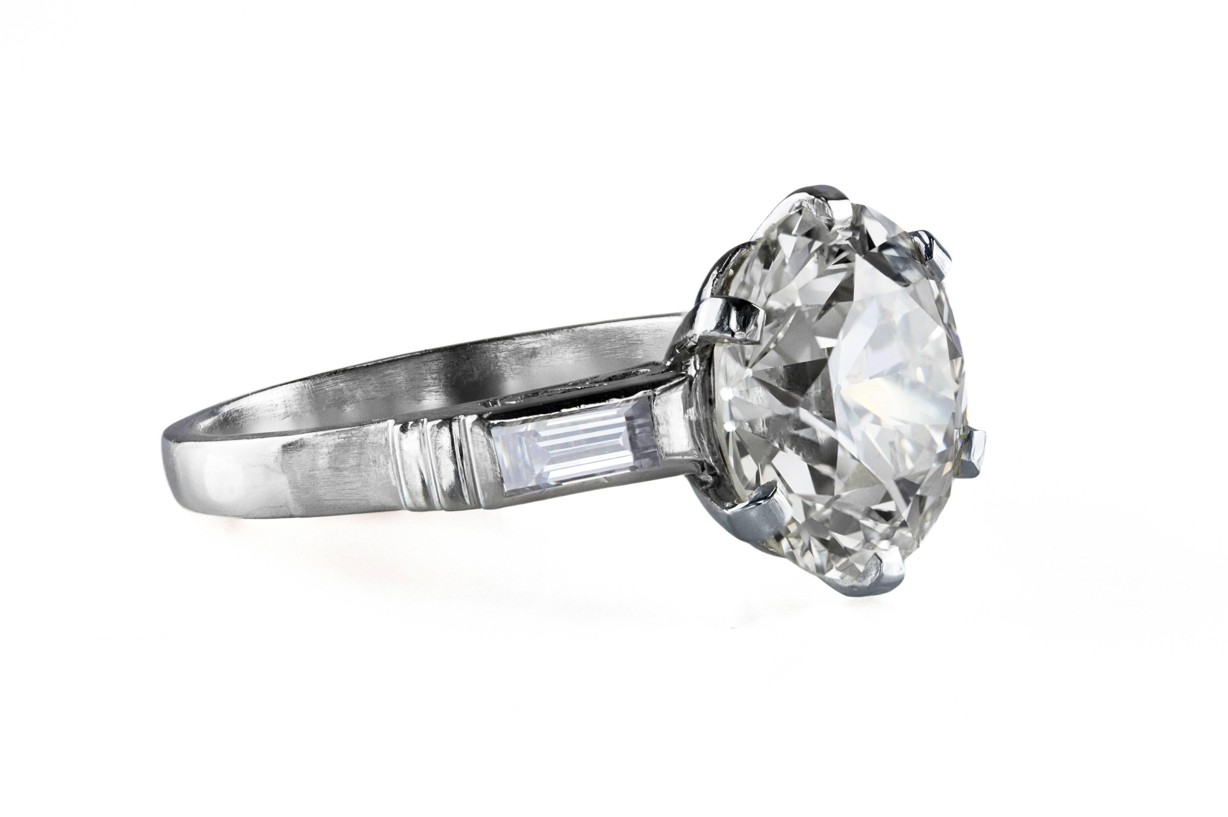 This gorgeous engagement ring features a 6.25 carat old European cut diamond center stone accented by a baguette diamond on each side. Weight of the baguette diamonds is 0.35 carats total. Set in a creative and antique looking 6 prong setting. Made