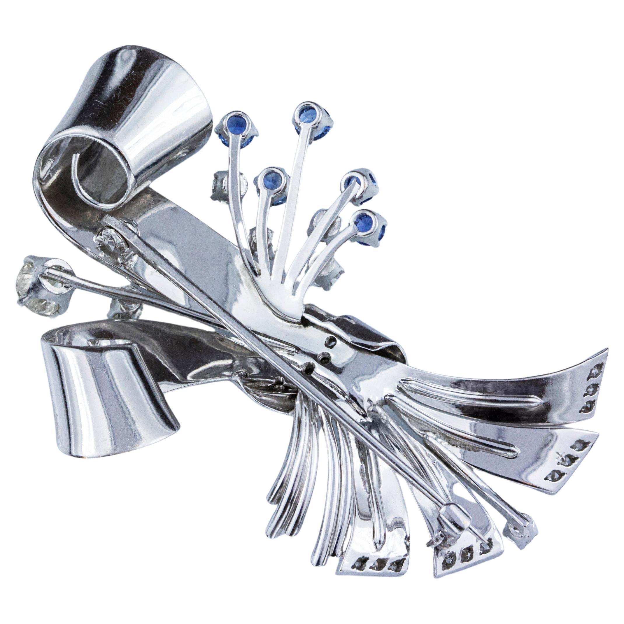 A wonderful ribbon brooch, featuring 29 old European cut diamonds weighing 1.00 carat total. Accented by 5 round cut sapphires weighing 0.50 carat total. Finely made with 14K white gold. 