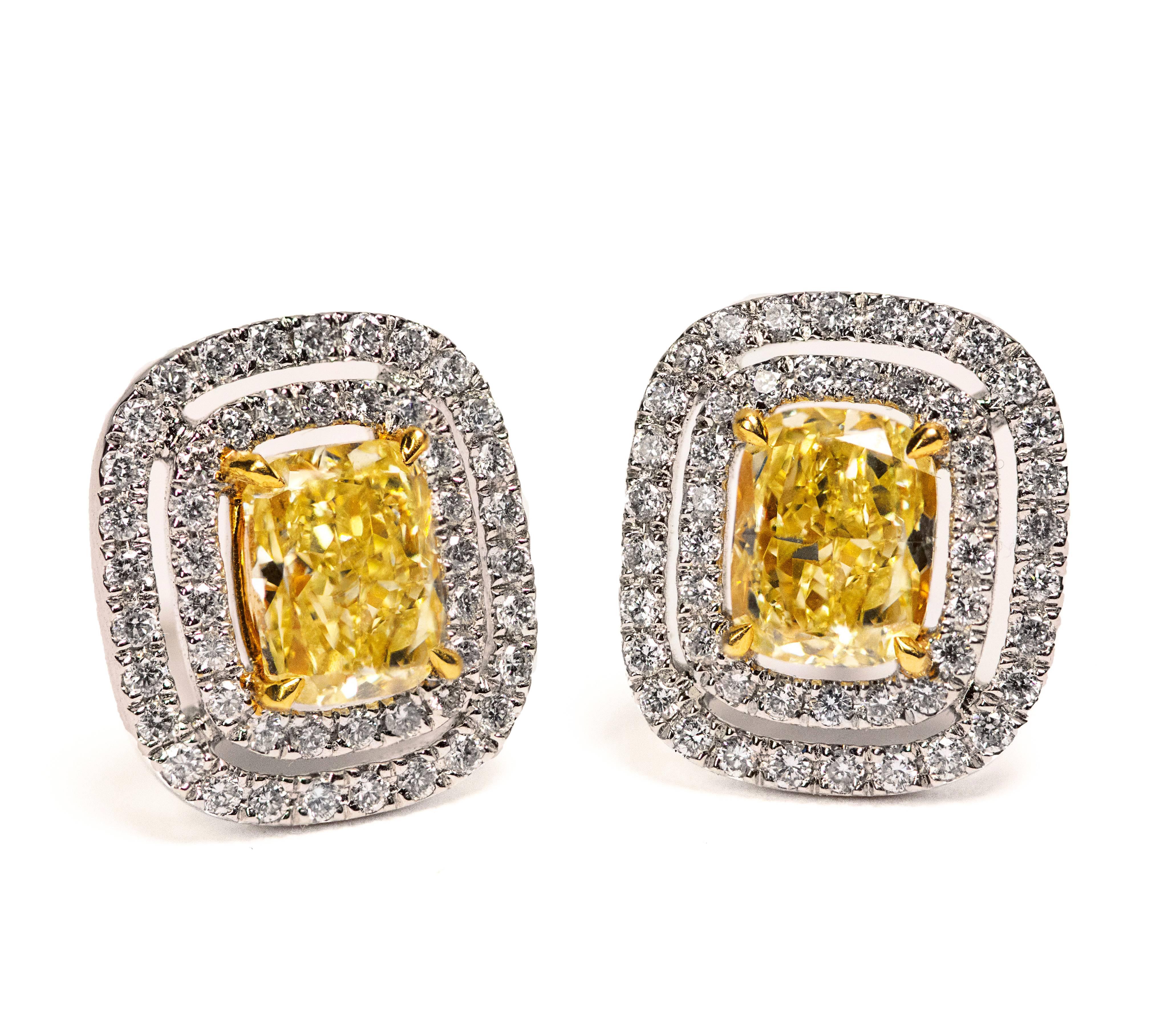 A classy and color-rich stud earrings features two cushion cut yellow diamonds weighing 1.01 and 1.03 carats total certified by GIA as Fancy Yellow in color and VVS2-VS2 in clarity. Set in four prong 18K yellow gold.  Each yellow diamond is