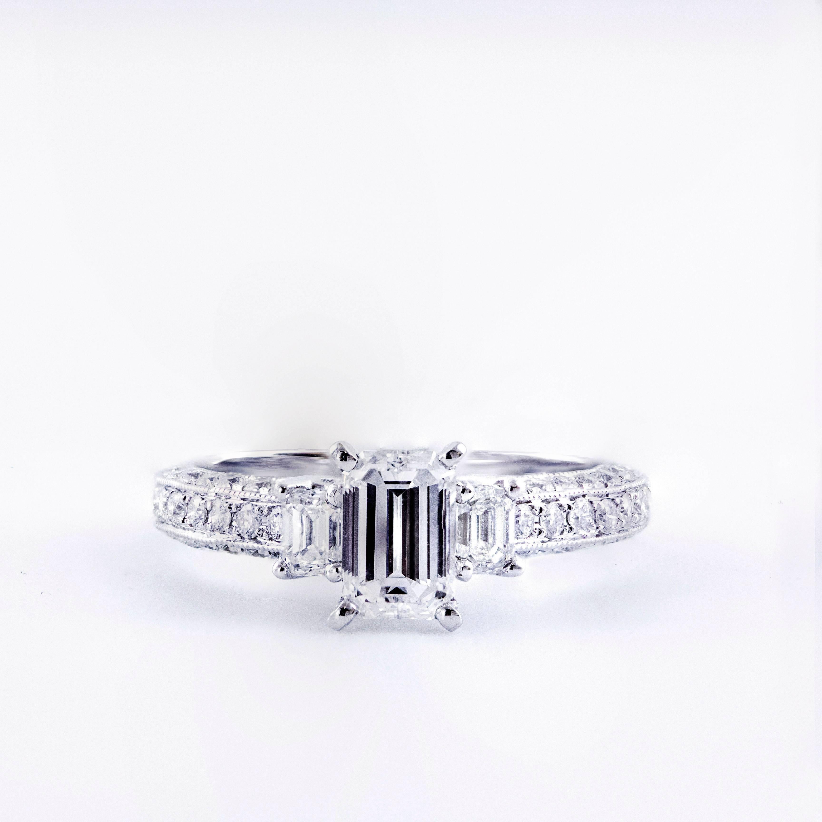 This set features an 0.81 carat emerald cut diamond center stone accented by an emerald cut diamond side stone one each side. Total weight of the side stones is 0.30 carats. Round brilliant diamonds set half way through the shank of the engagement