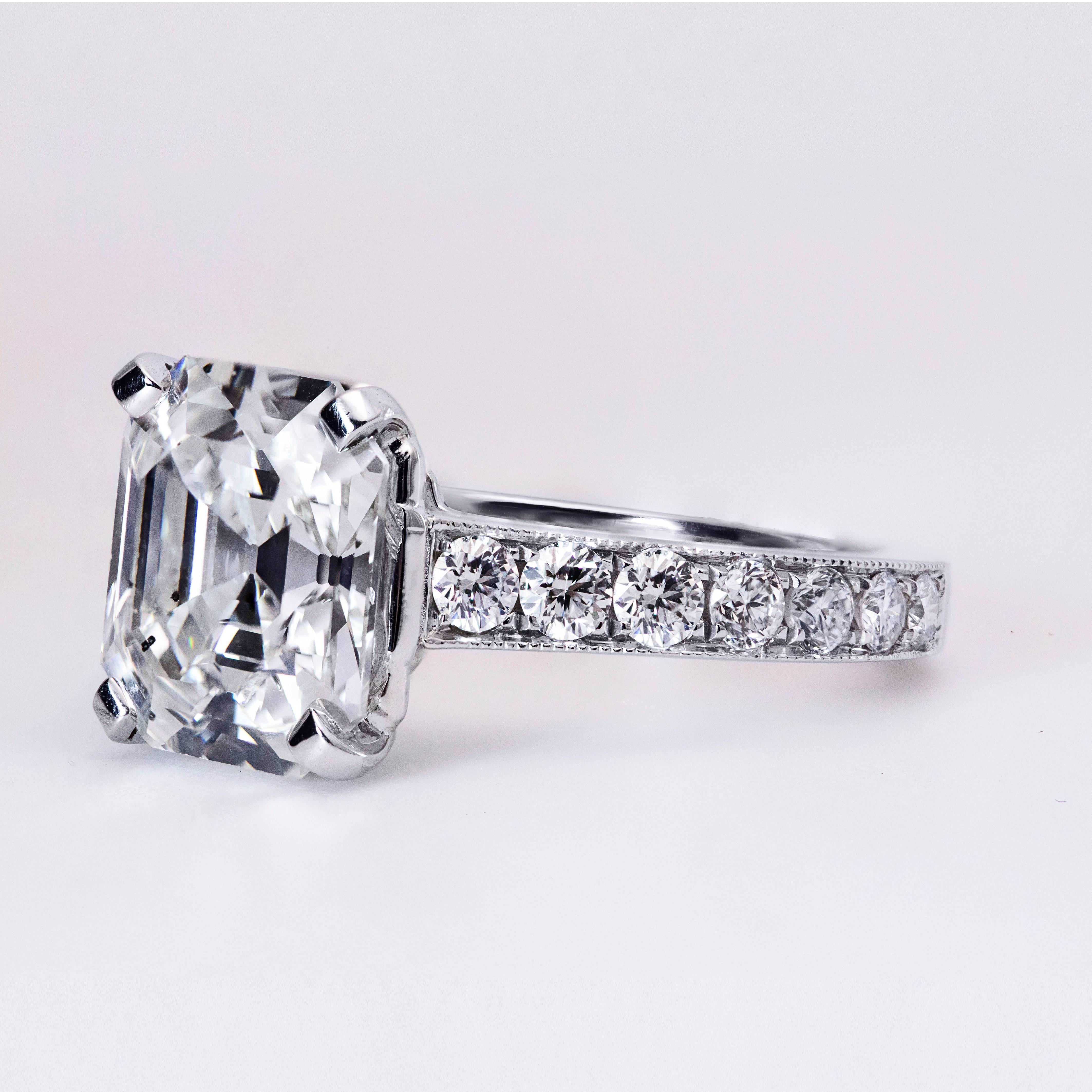 This ring features a 3.59 carat asscher cut diamond center stone that HRD certified as H color and SI1 clarity. The shank is set with 7 round brilliant diamonds on each side. Total weight of the accent diamonds is 0.70 carats. Made in Platinum. Size