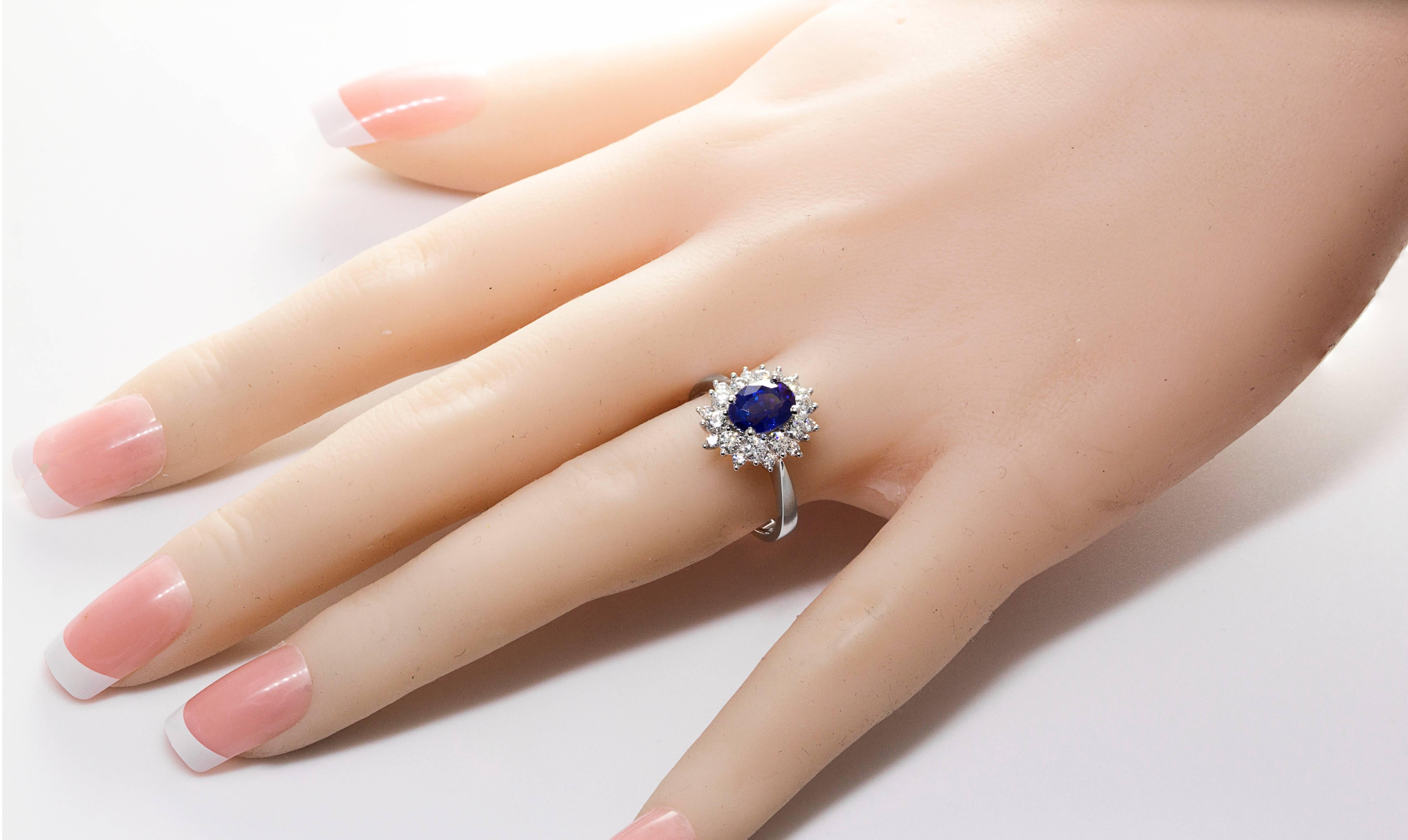 Gorgeous ring set with a 2.09 carat oval cut blue sapphire center stone. Surrounding the center stone are brilliant round cut diamonds set in a flower style halo setting. Made in 18k white gold.

Style available in different price ranges. Prices are