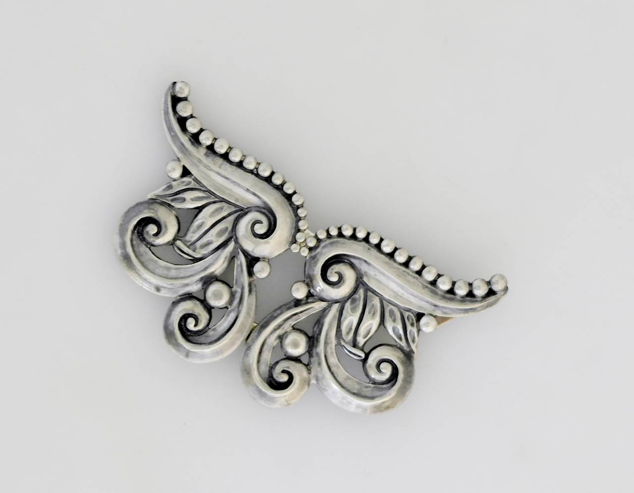 Being offered is a large sterling silver brooch by Margot de Taxco, of Mexico. Double hinged, two-sided large brooch, entirely handmade, with elegant scroll motifs. Dimensions: 3 7/8