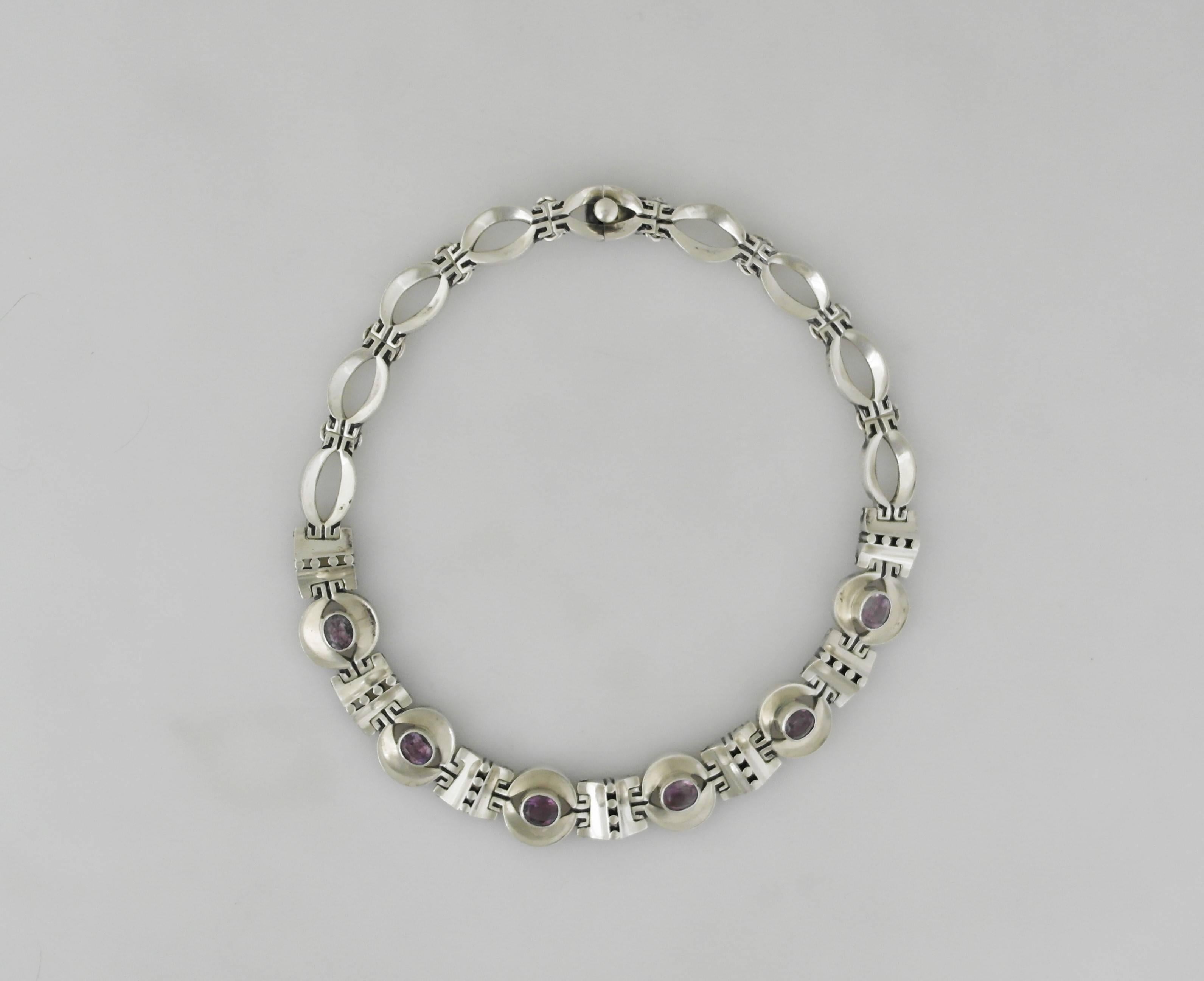 Being offered is a sterling silver necklace made by Los Ballesteros of Taxco, Mexico. Comprising pierced & circular alternating links; six of which have bezel set cabochon amethysts; tongue & box closure. Dimensions: 15 inches x 3/4 inch wide.