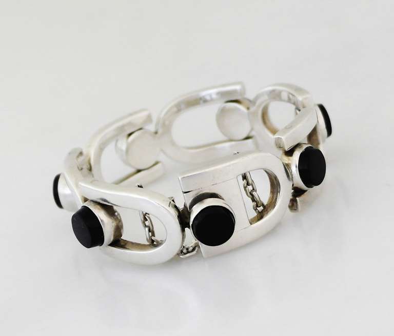 Being offered is a circa 1960s .970 silver bracelet by Hector Aguilar of Taxco, Mexico. Modernist piece with U-shaped links bearing applied onyx stones; tongue & box closure with security chain. Dimensions: 3/4