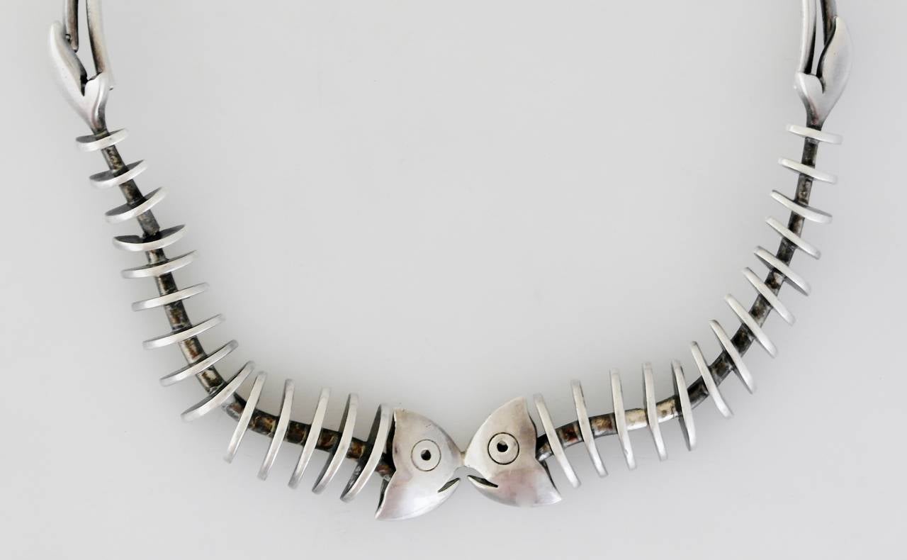 Being offered is a circa 1963 .970 silver (better than sterling) choker necklace by Antonio Pineda of Taxco, Mexico. Comprising two conjoined skeletal fish motifs supported by elongated silver wire; tongue & box closure. Dimensions: inner - 15 1/2