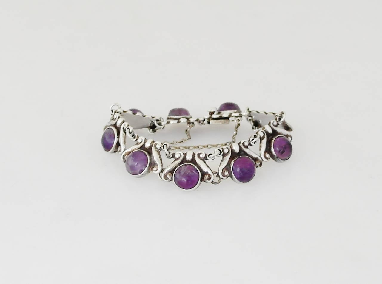 Being offered is a circa 1968 sterling silver bracelet by Los Castillo of Taxco, Mexico. Each link decorated with a scroll & bead design and bezel set amethyst cabochons. Dimensions: 3/4