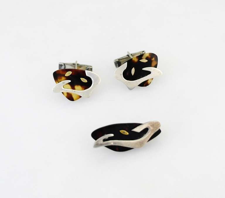 Being offered is an exceedingly rare circa 1954 cufflinks & tie clip set by Enrique Ledesma of Taxco, Mexico. Consisting primarily of shell with applied silver and brass biomorphic shapes. Dimensions: each cufflink 1 inch by 5/8 inch; tie clip 1 1/2
