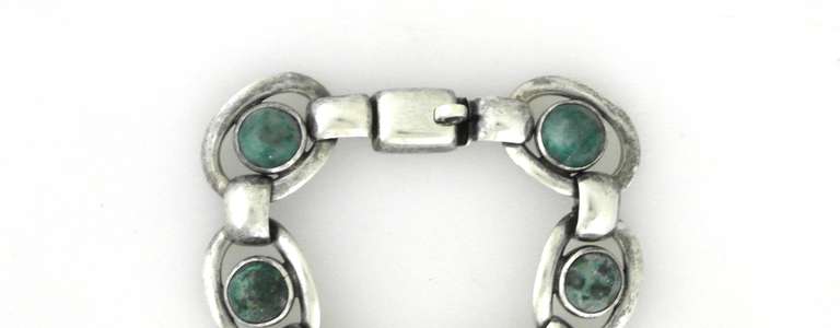 Being offered is a circa 1954 .940 silver bracelet by Hector Aguilar of Taxco, Mexico. Modernist design with each loop link supporting a natural stone (malachite, Mexican Jade); tongue & box closure. Dimensions: 7 1/4
