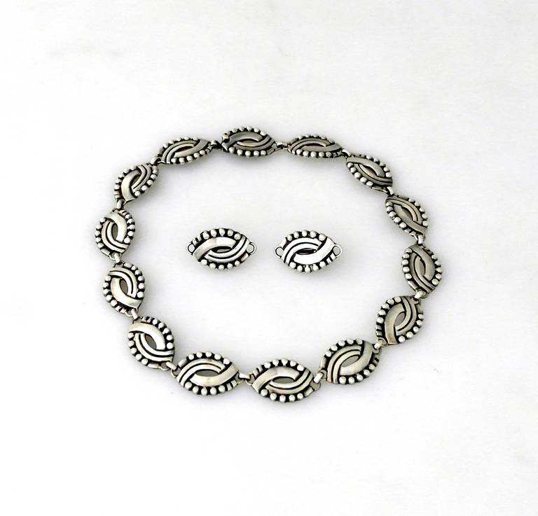 Being offered are a sterling silver necklace & earrings set by Hector Aguilar of Taxco, Mexico. the links a swirl of silver, decorated with beads and piercing.  The screw back earrings have the same motif.  Dimensions of necklace  inches long. 