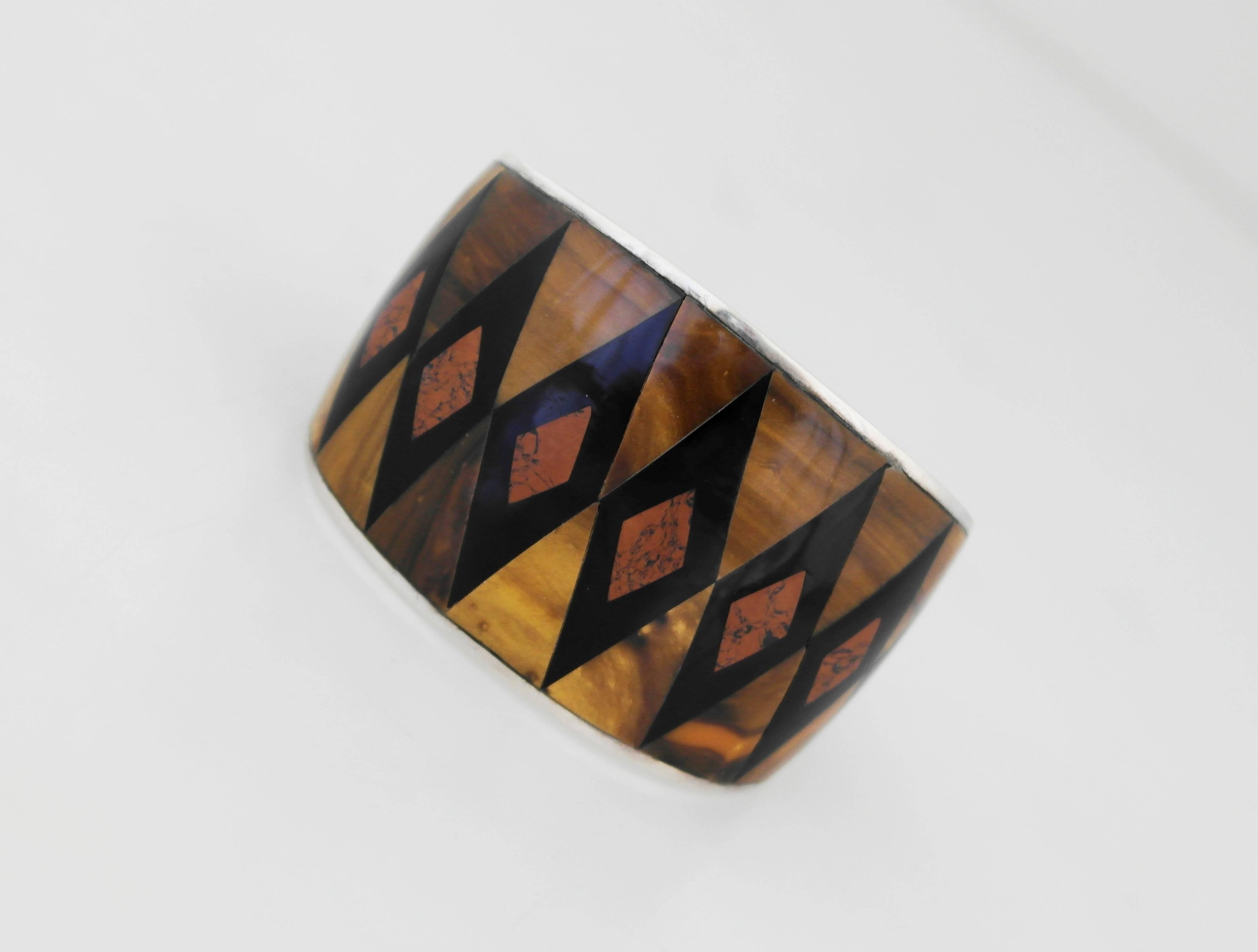 Being offered is a circa 1940 sterling silver bracelet by Bernice Goodspeed of Mexico. Incredible cuff bracelet designed with tiger's eye and onyx inlay. Dimensions: wearable 6 1/2 inches x 1 3/4 inches wide; 1 1/4 inch opening. Marked as