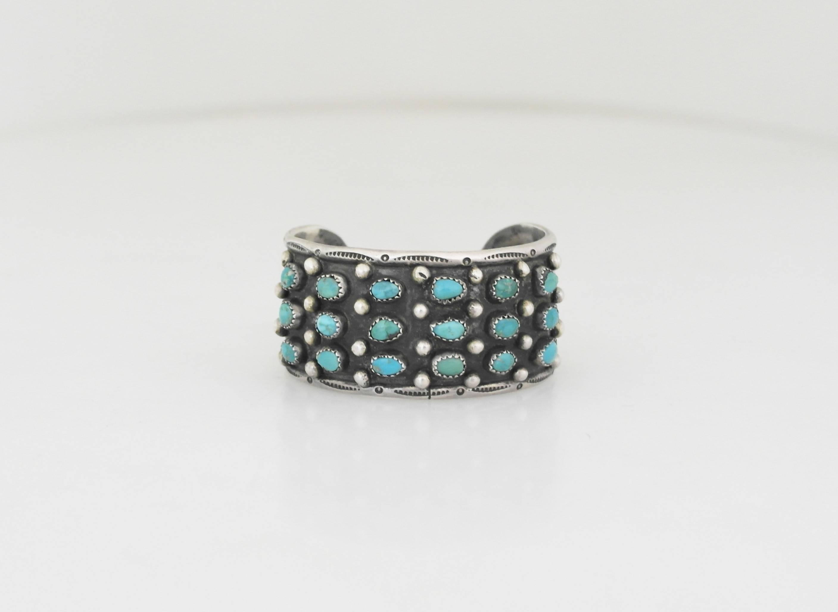 Being offered is a sterling silver cuff bracelet by Native American silversmith, Roger Skeets. Bracelet decorated with rows of bezel set turquoise stones & applied dots. Dimensions: 1 1/4 inches wide x 6 inches (wearable). Marked as illustrated. In