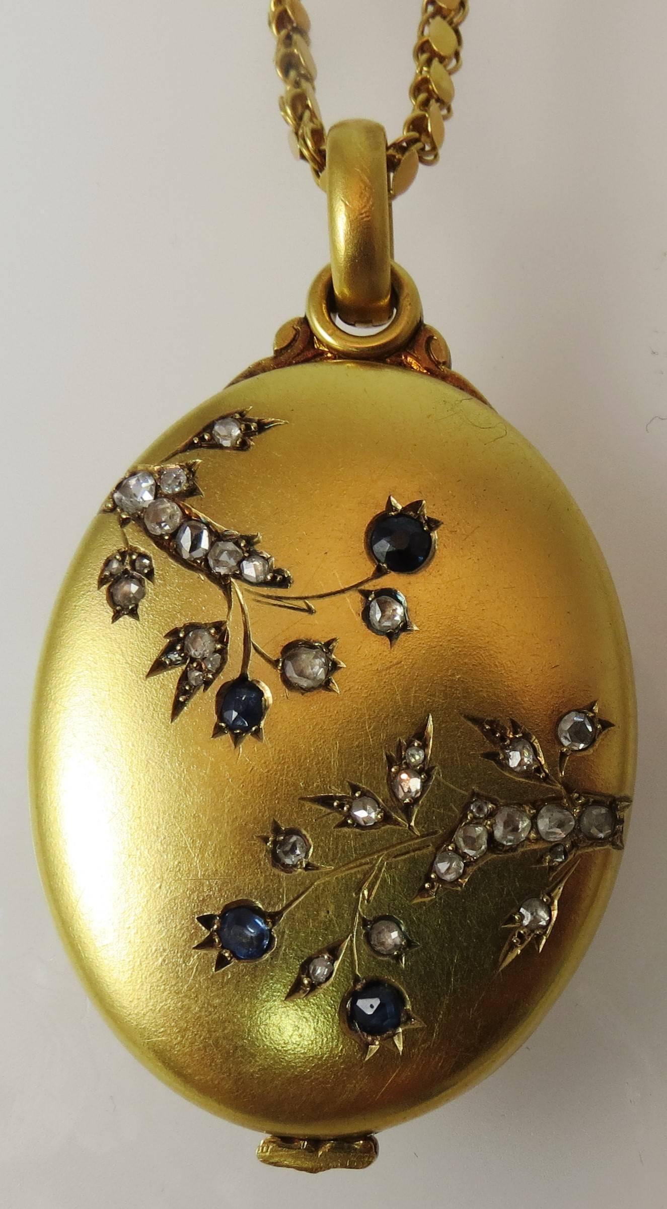 Beautiful Vintage 18K yellow gold oval locket, with floral motif, set with 31 rose cut diamonds and 4 rose cut blue sapphires, monogram engraved on back suspended from 18K yellow gold vintage chain, 31 inches long. Can be sold individually.