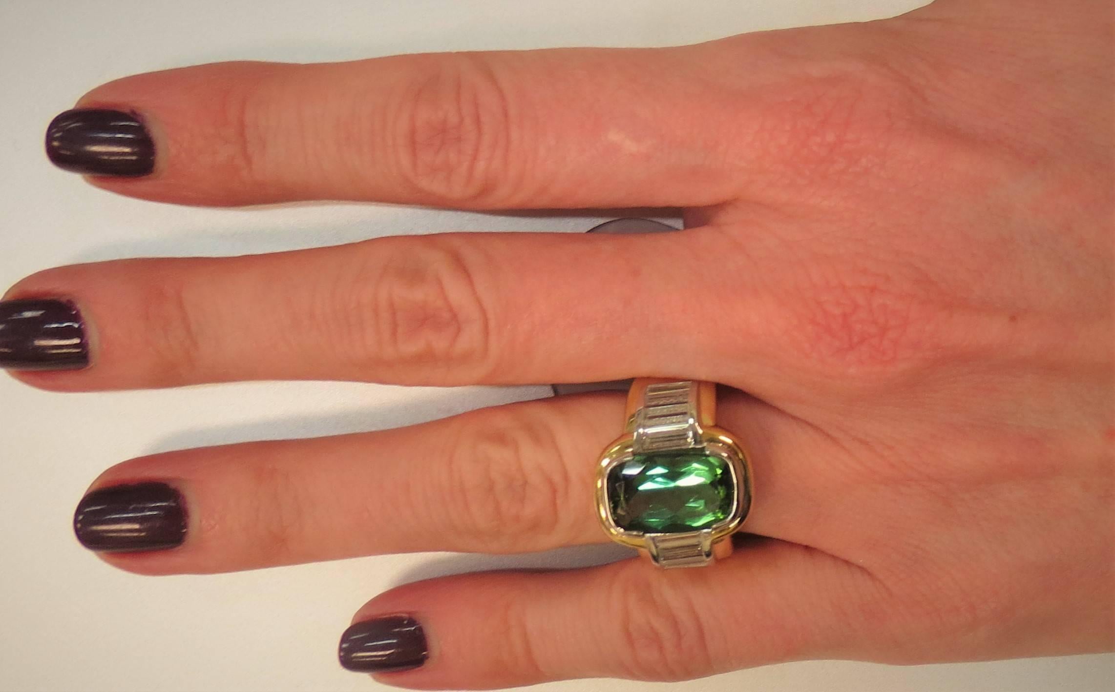 Contemporary 18K yellow gold ring with platinum inner bezel set with faceted green tourmaline weighing  6.07cts and 13 baguette diamonds weighing about 1.44cts total