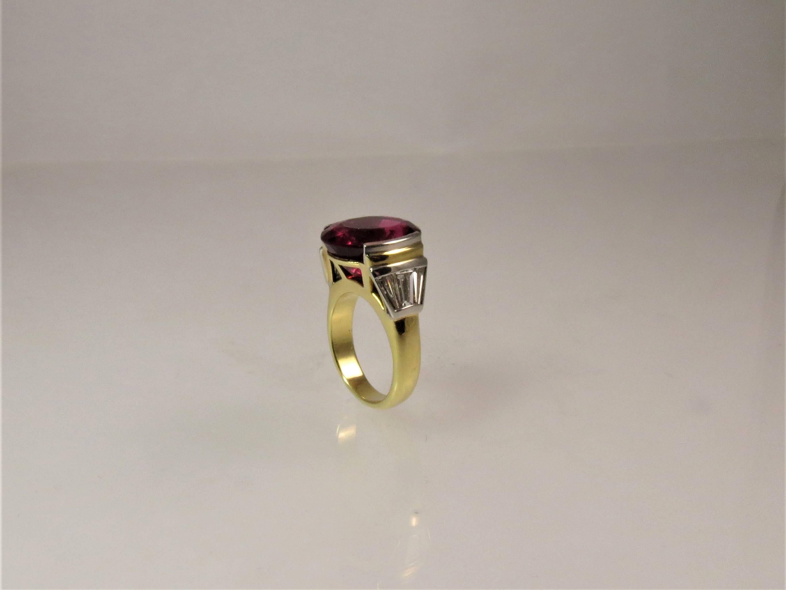 Susan Berman, 18K yellow gold and platinum ring set in center with oval 
rubellite weighing 10.38cts and flanked by 6 baguette diamonds weighing 1.30cts, G-H color, VS clarity. 
Finger size 6, may be sized