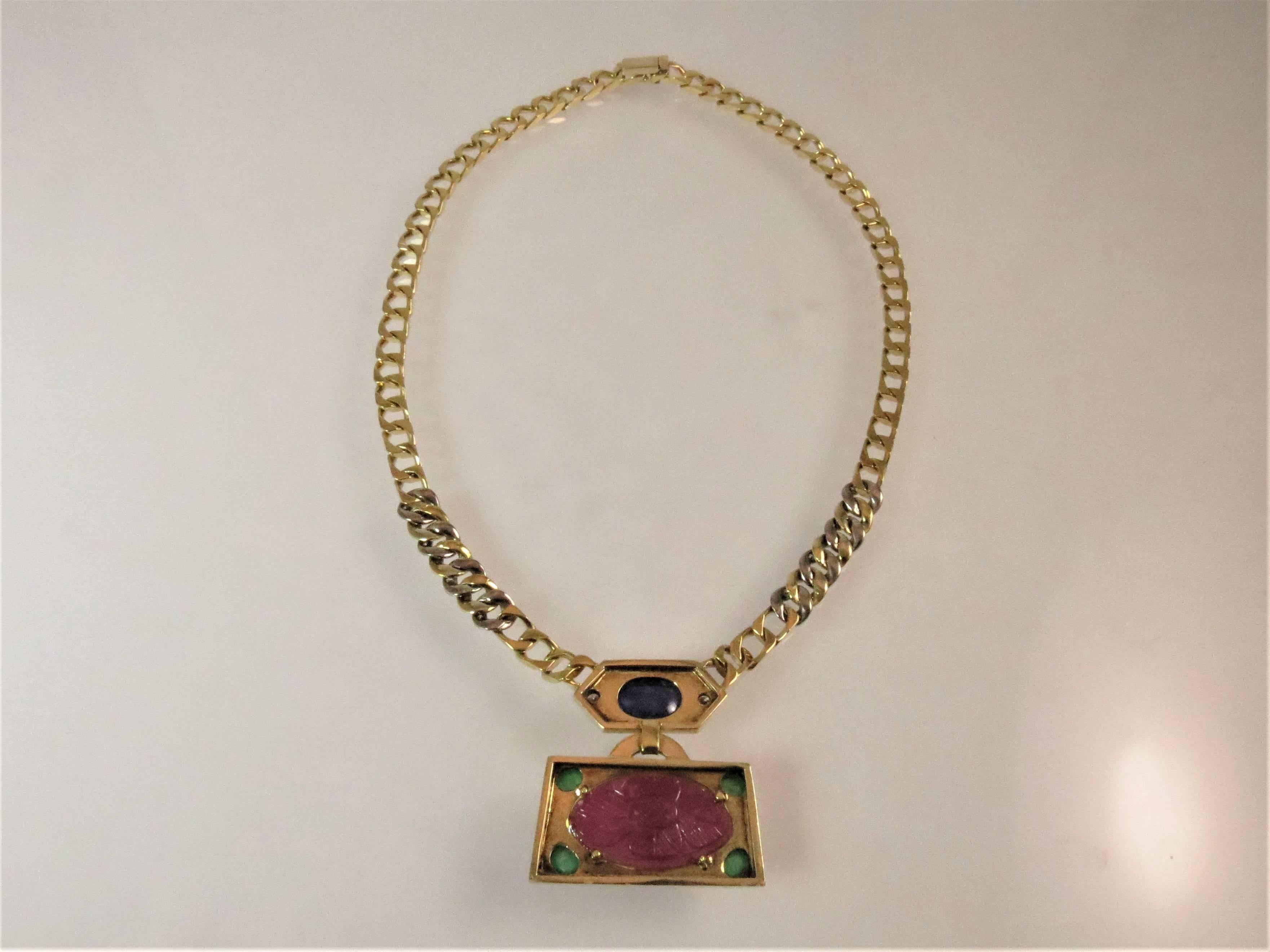 18K yellow gold curb link necklace with carved ruby weighing 21.75ct, cabochon sapphire weighing 3.95cts, 4 cabochon emeralds weighing 1.50ct, and 18 full cut round diamonds weighing .50cts, GH color, VS clarity.