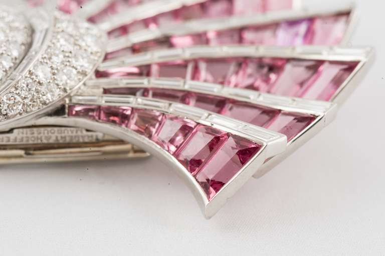 Signed Trabert & Hoeffer Mauboussin Pink Tourmaline and Diamond Platinum  Brooch, set with 45 calibre cut pink tourmalines weighing about 15 carats, 66 straight baguette diamonds weighing about 8.50 carats, G color, VS clarity, 42 full cut round