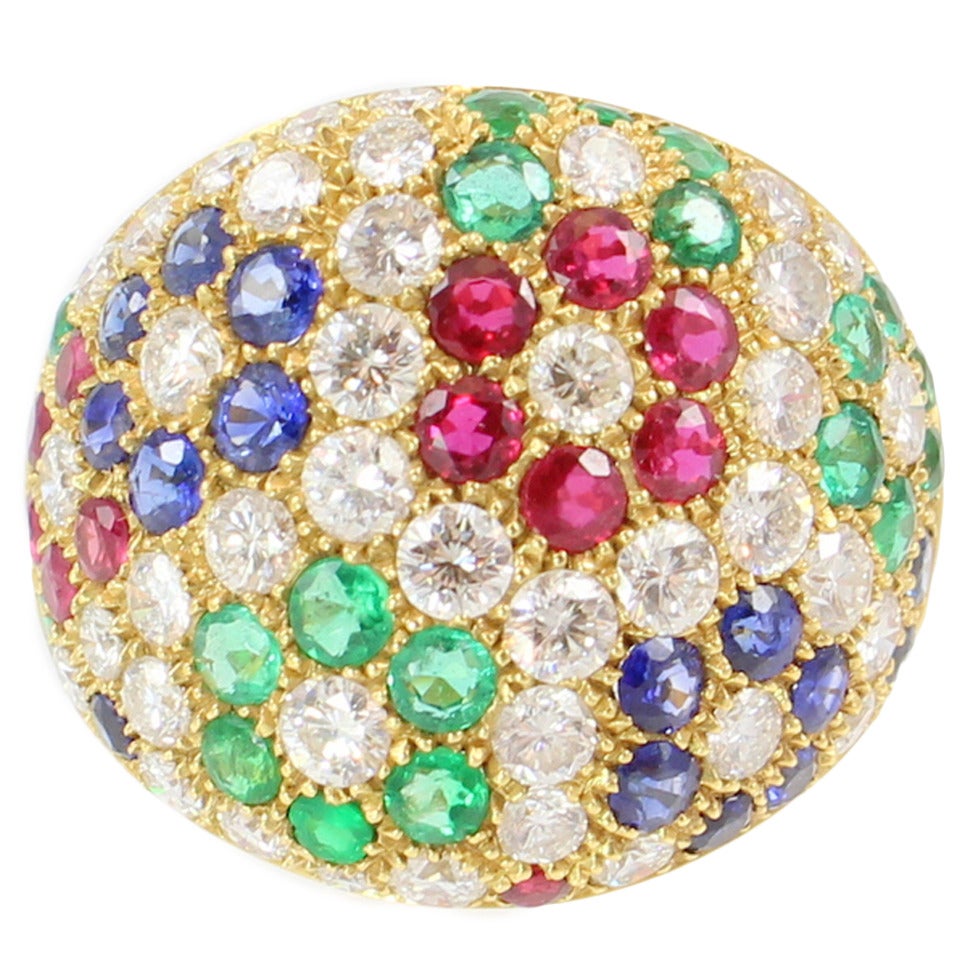 18K yellow gold bombe ring, flower pattern set with 40 full cut round faceted diamonds weighing 2.15 carats, 13 faceted rubys weighing .84 carats, 15 faceted blue sapphires weighing 1.02 carats, 19 faceted emeralds weighing 1.12 carats

Finger