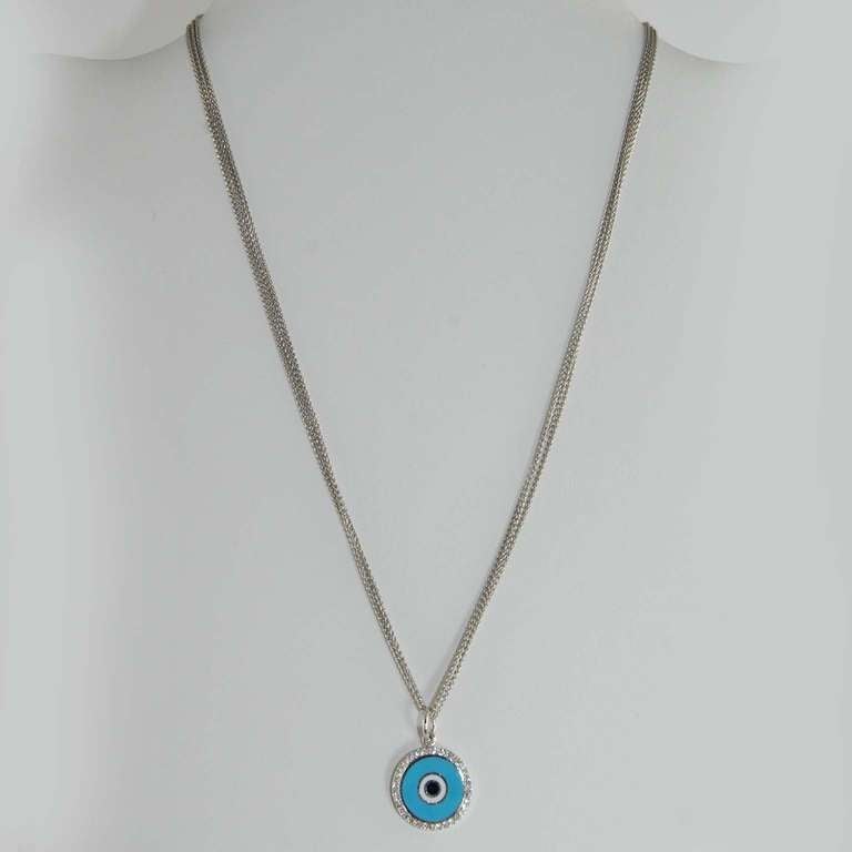 Aaron Basha 18K white gold light blue round enamel evil eye diamond charm with full cut round diamonds weighing .23 carats suspended from a 18K white gold three strand chain.