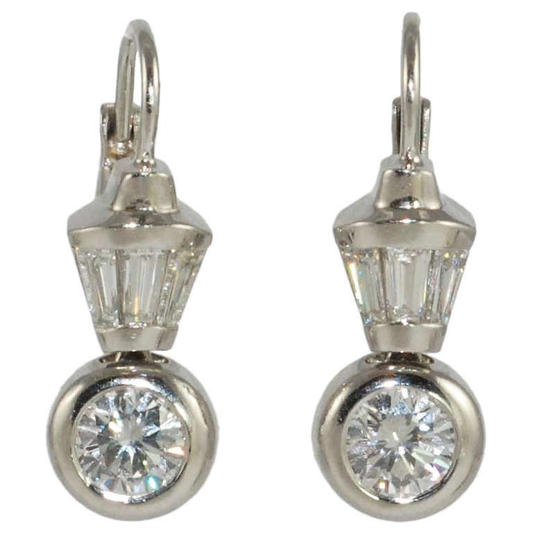 Diamond platinum wire drop earrings, by Susan Berman, bezel set with 2 round diamonds weighing 1.48 carats, G color,  VS clarity and 6 matching tapered baguette diamonds weighing .91 carats  suspended from a platinum wire with lever backs.