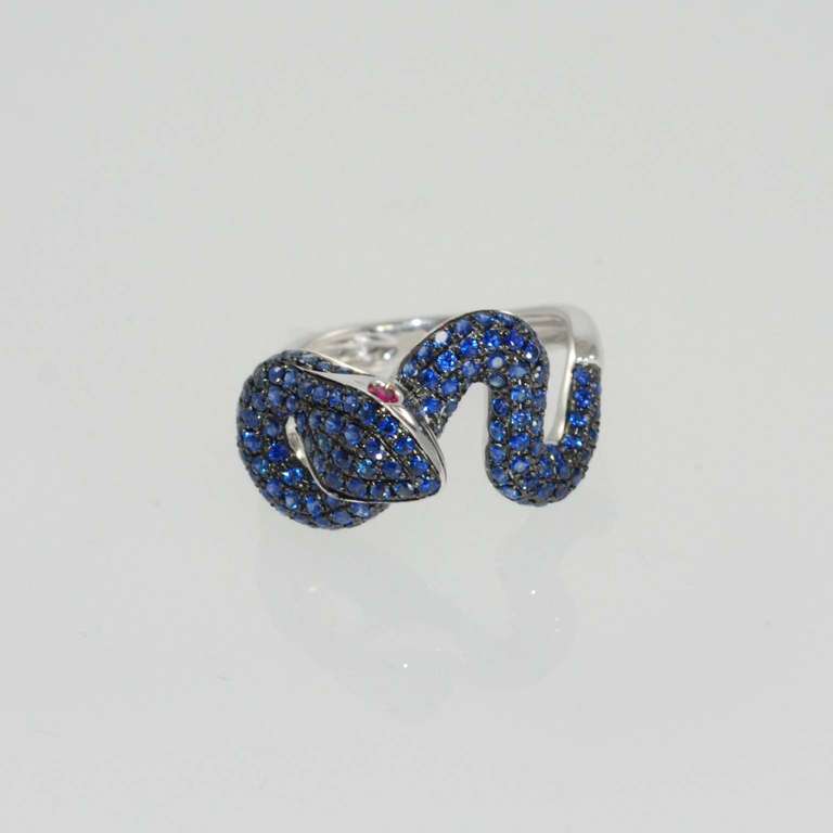 18K white gold serpent ring set with blue sapphires weighing 1.32 carats and two ruby eyes weighing .08 carats. Finger size 7. May be sized