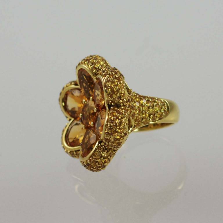 18K yellow gold flower design ring, prong and bezel set with 6 oval faceted citrines and 1 round citrine weighing about 11 carats total, surrounded by 243 prong set yellow sapphires weighing 14.86 carats total

Finger size 6.5. May be sized.