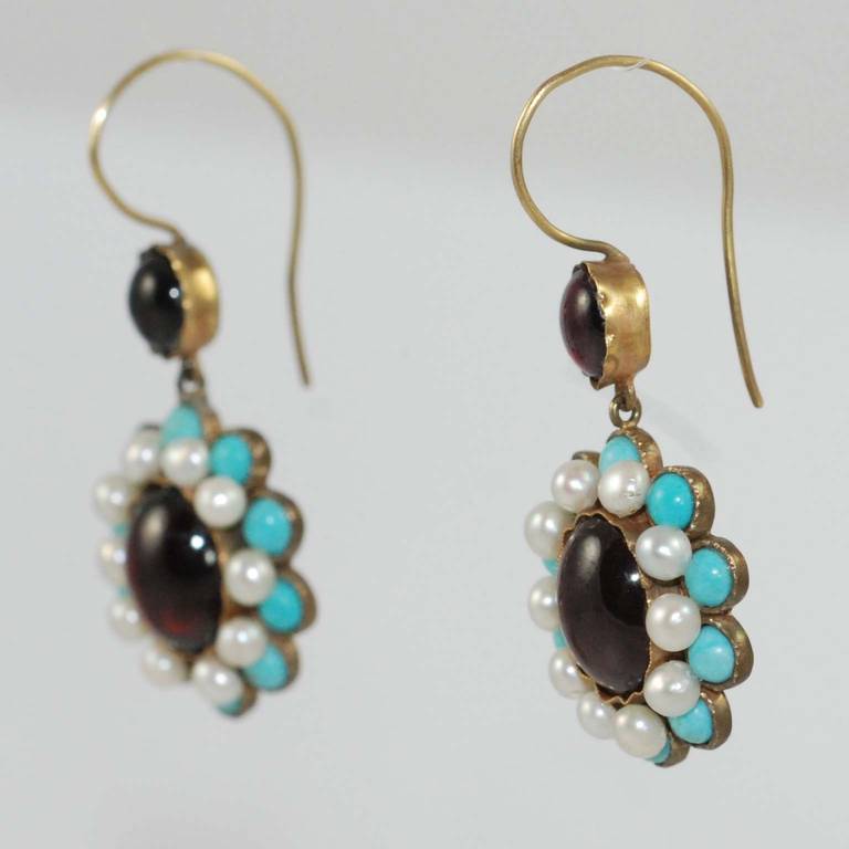 Victorian 15K yellow gold earrings set with twenty cabochon turquoise, four cabochon garnets, and twenty natural pearls with elongated shepherd hook backs.