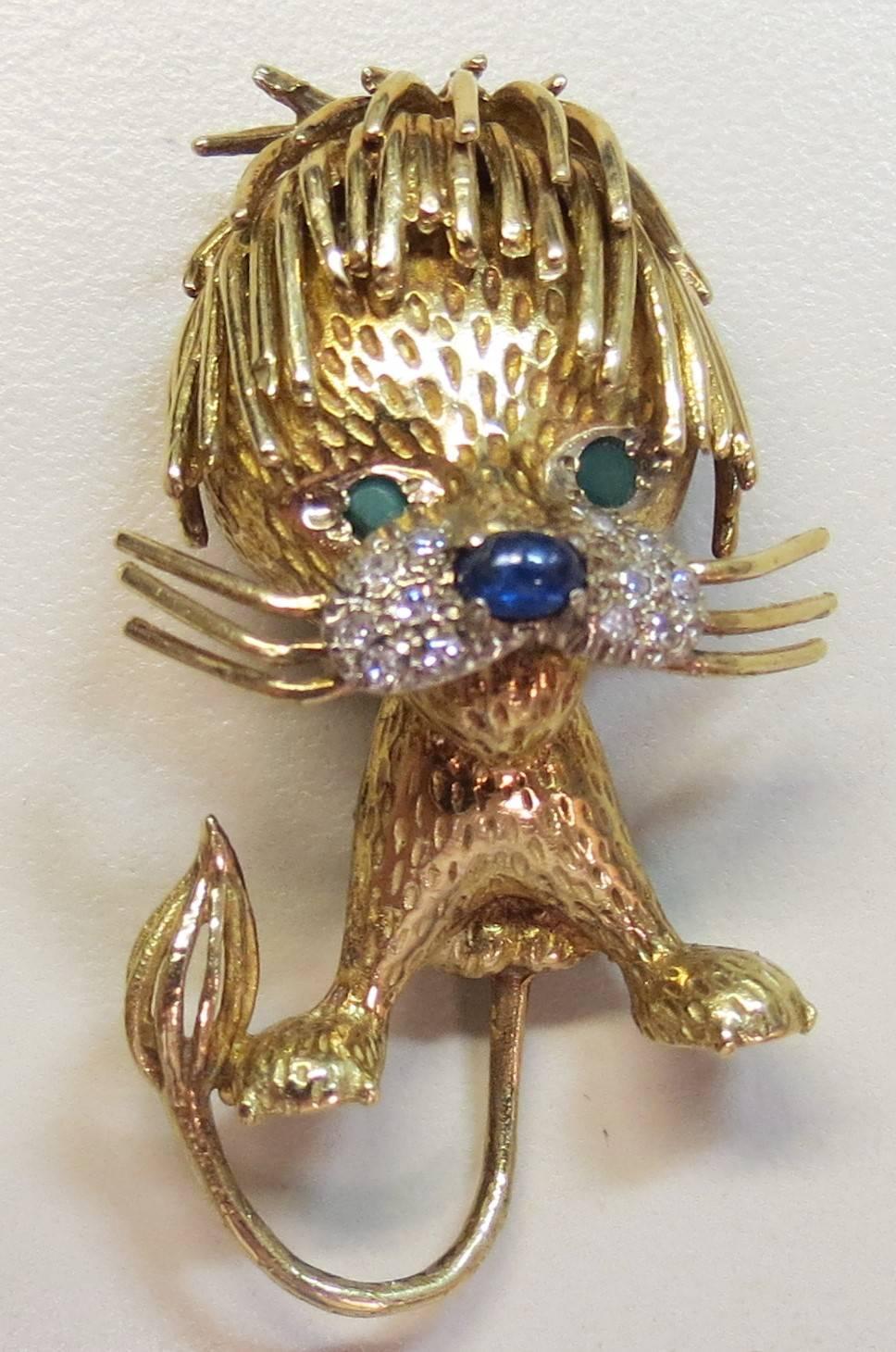 Delightful 18K yellow gold toussle headed lion pin, with 12 round diamonds weighing approximately .12cts, 2 round green onyx eyes and one oval blue sapphire on nose.